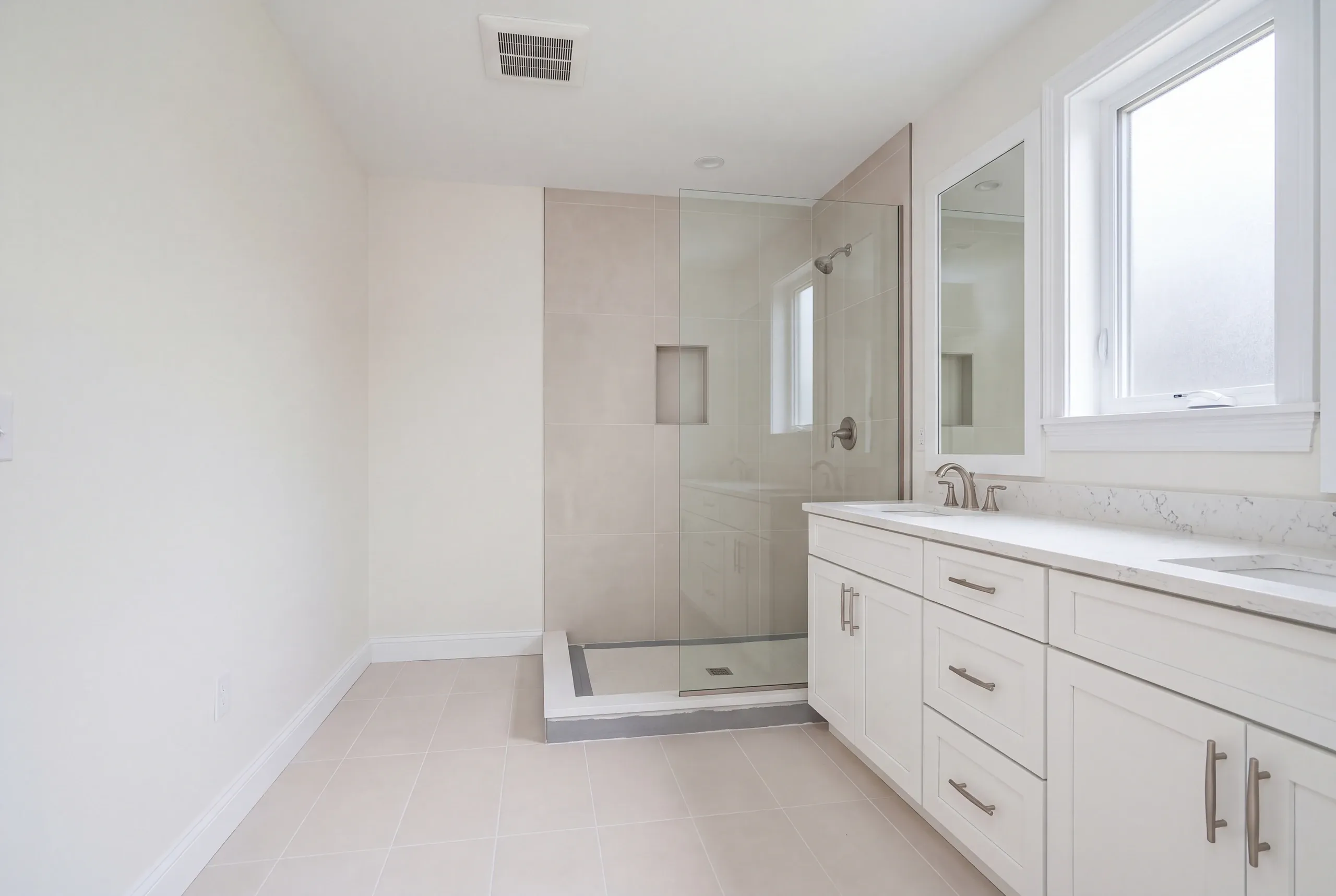 Bathroom remodeler Bath Maine: double vanity bathroom with a beige large tile shower whose curb is not yet tiled
