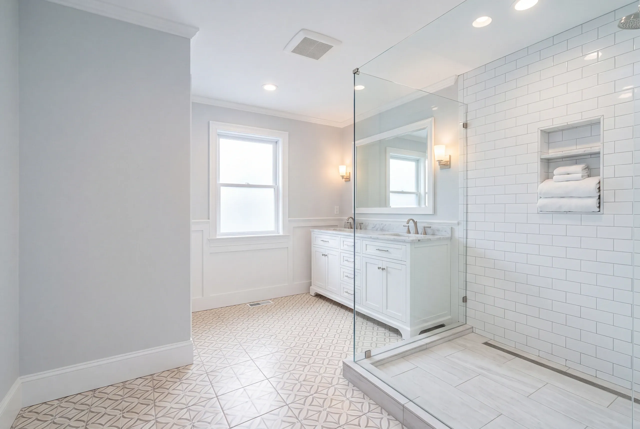Bathroom remodeler Belfast Maine: bathroom with patterned cement-look floor tile, a white double vanity and a glass subway tile shower