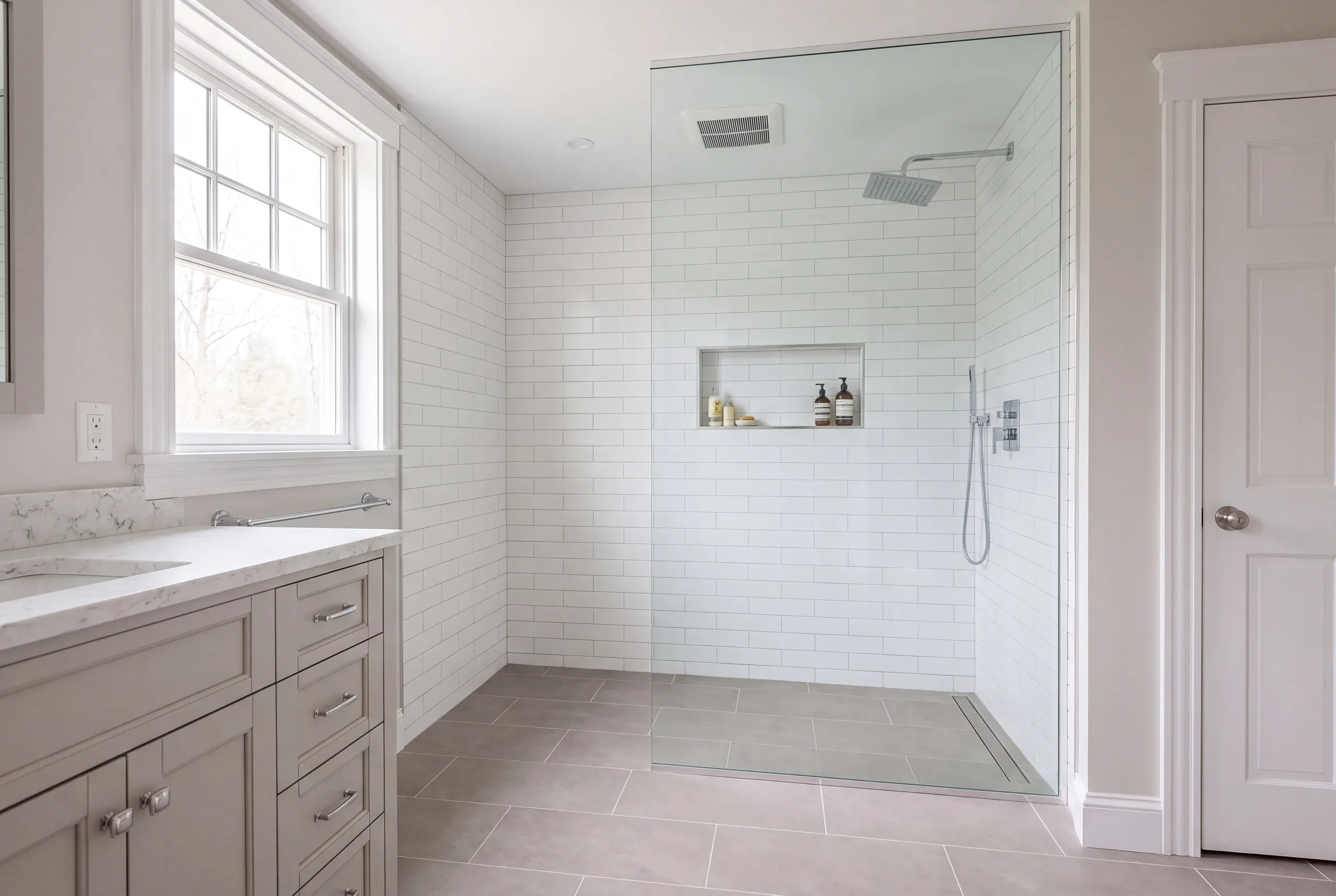 Bathroom renovation contractor Bucksport Maine: finished walk-in shower with a rain head, handheld spray and linear drain behind one glass panel