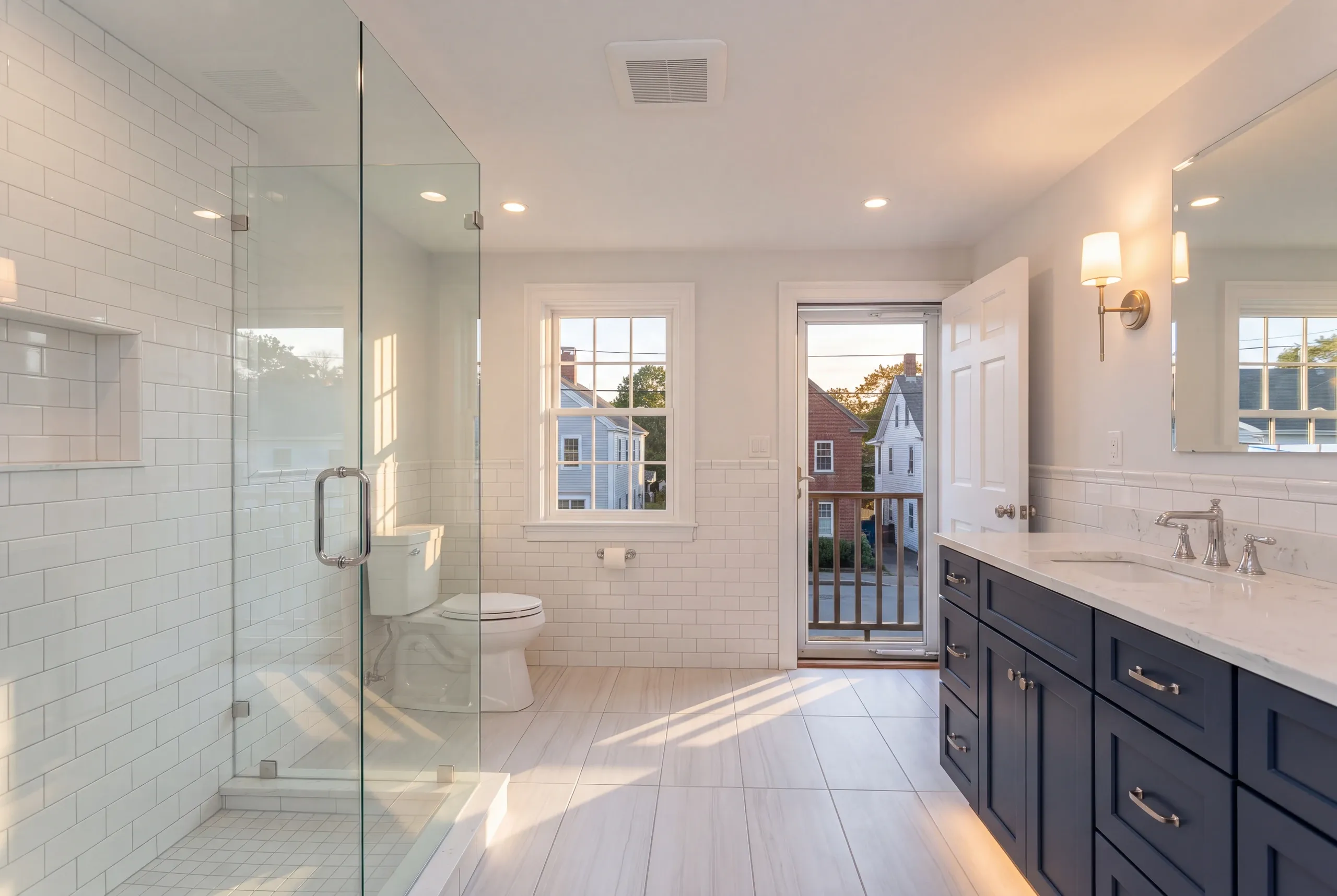 Bathroom remodeling in Damariscotta, ME: bathroom with a frameless glass shower, navy double vanity and a door out to a small balcony