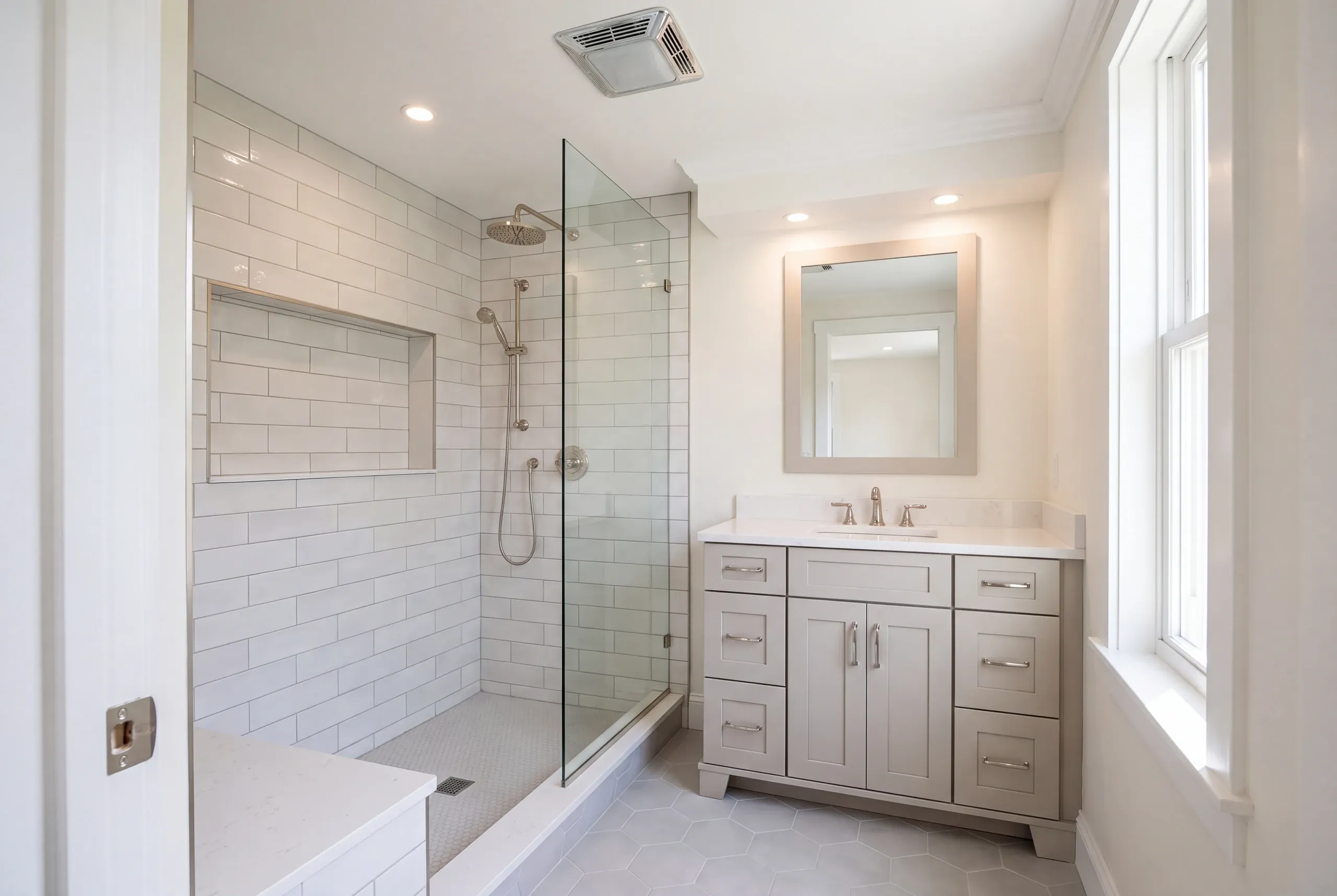 Bathroom remodeling contractor Damariscotta Maine: compact bathroom with a rain head subway tile shower, stone-look ledge and gray shaker vanity