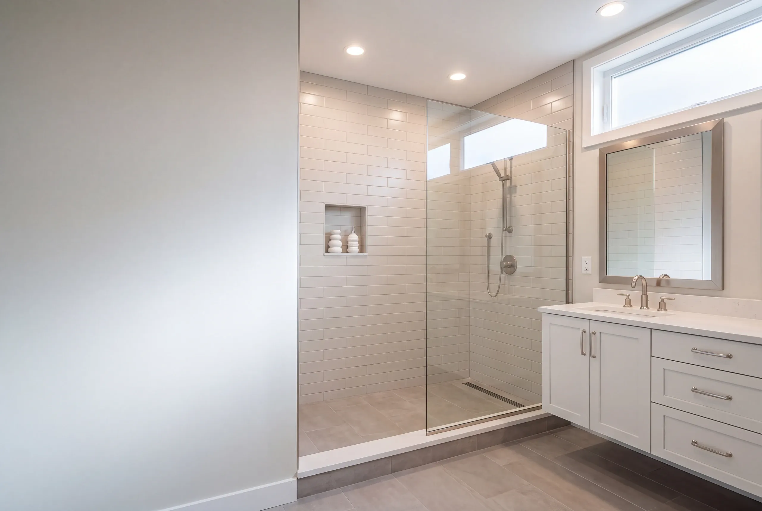 Bathroom remodeler Gardiner Maine: bathroom with a glass panel subway tile shower, linear drain and a floating white vanity