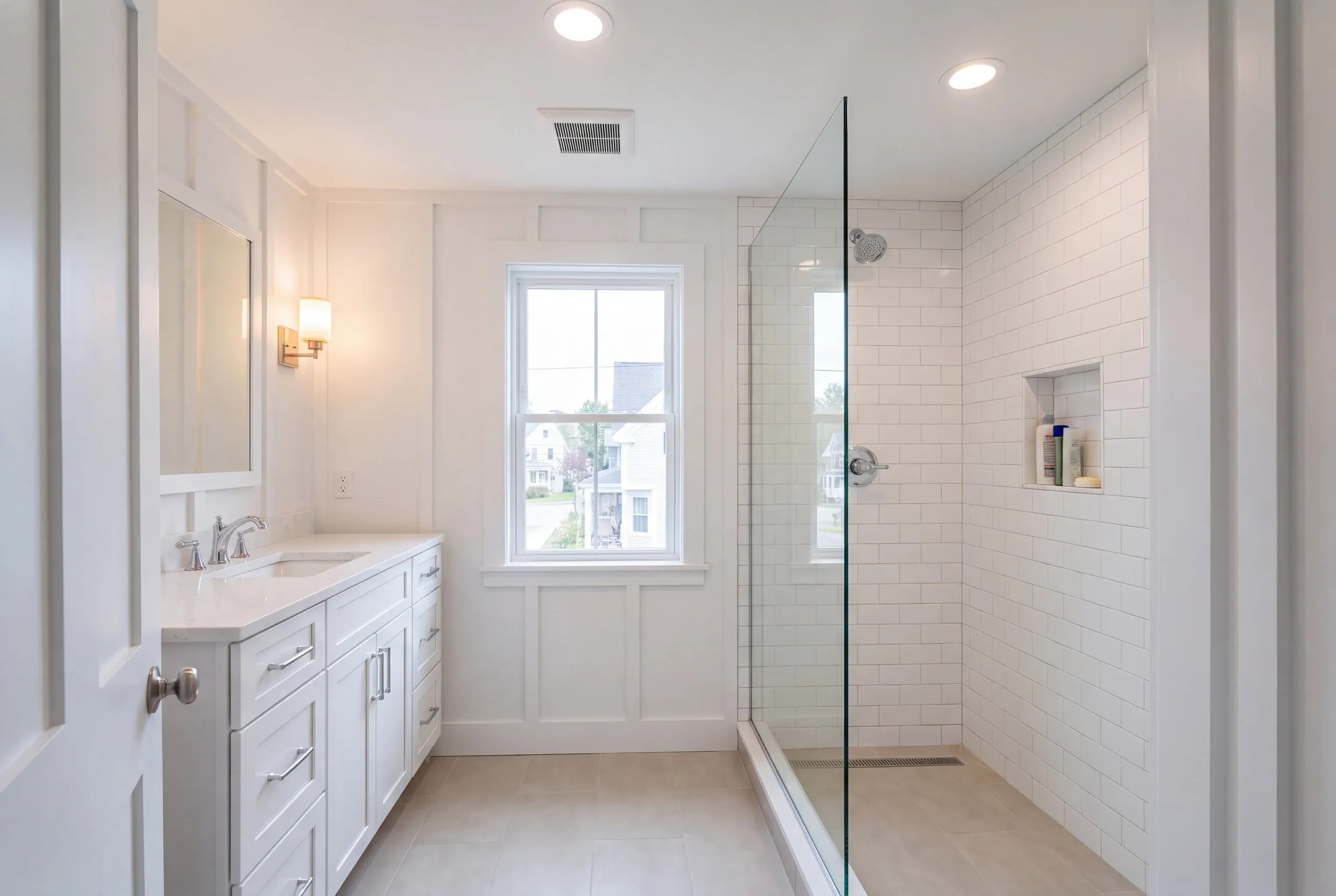 Bathroom remodeler Pittsfield Maine: board and batten bathroom with a white vanity and a glass subway tile shower with linear drain