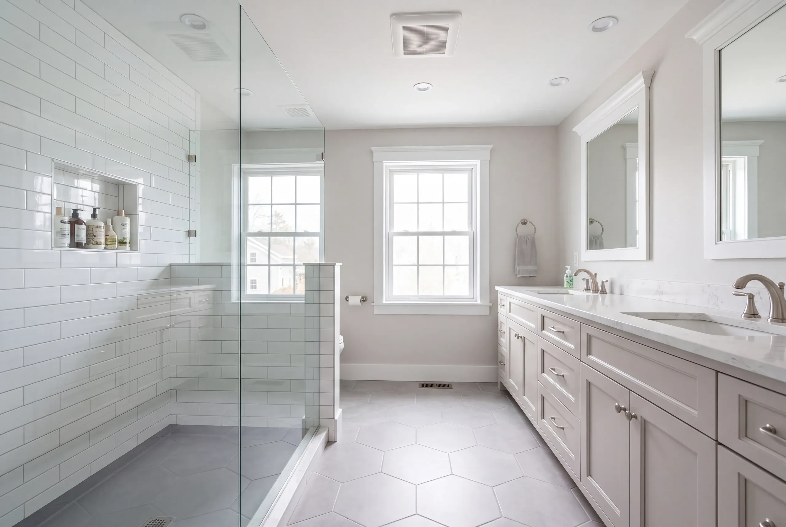 Bathroom renovation contractor Rockland Maine: bathroom with a subway tile shower, gray double vanity, hex floor and two windows