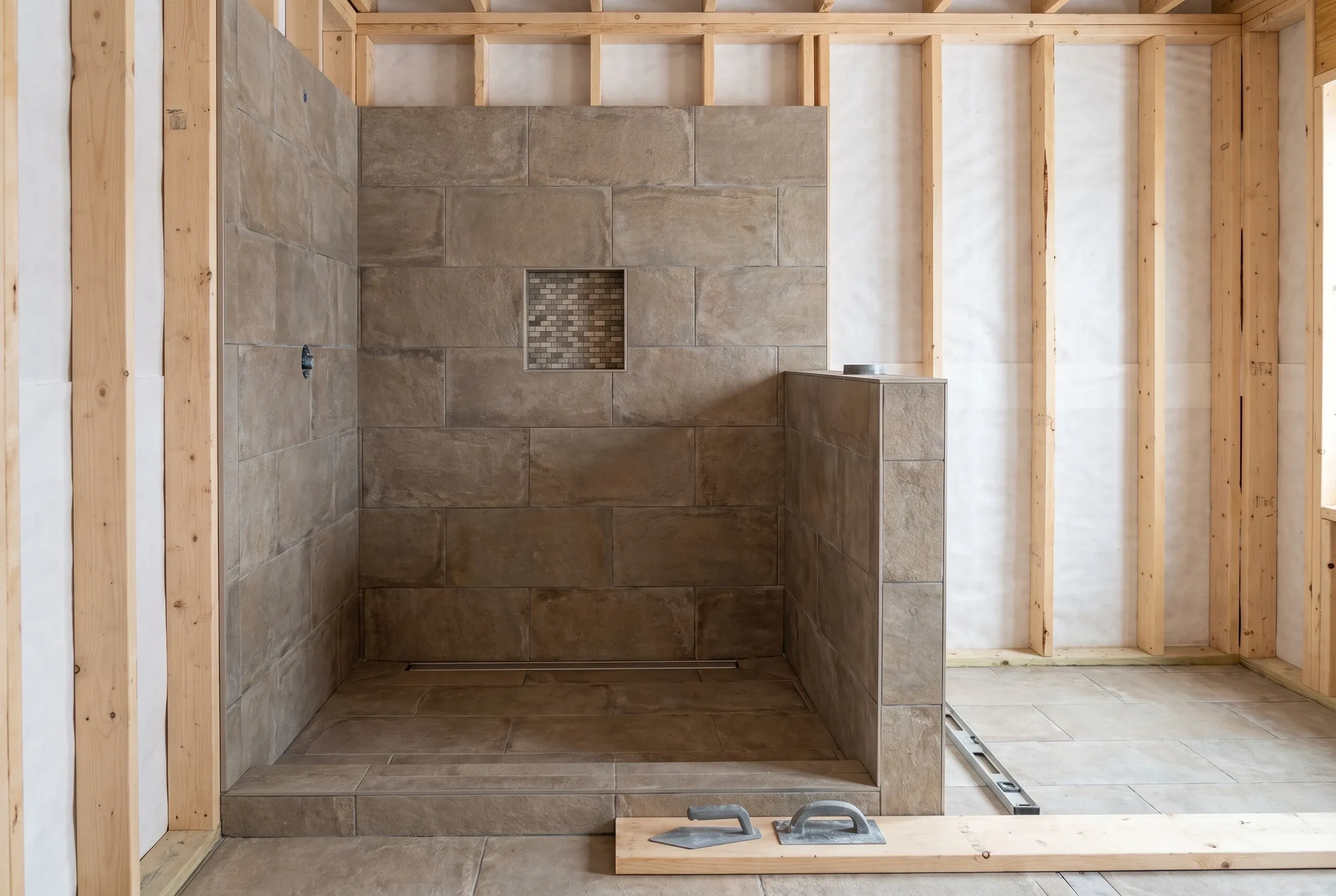 Bathroom renovation contractor Rockport Maine: large-format tile shower with a linear drain, mosaic niche and tiled half wall