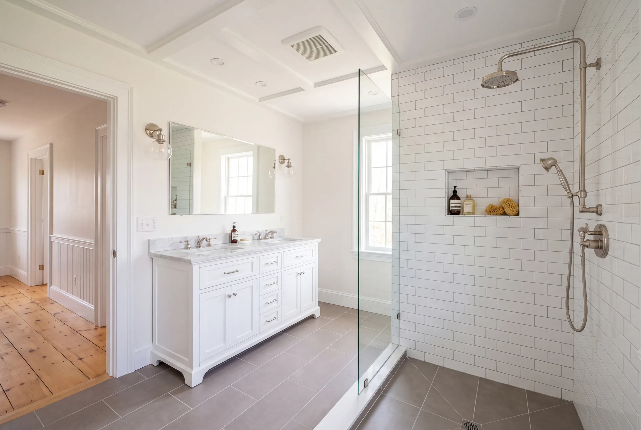 Bathroom remodeler Searsmont Maine: bathroom with an exposed rain shower riser, subway tile, white double vanity and coffered ceiling