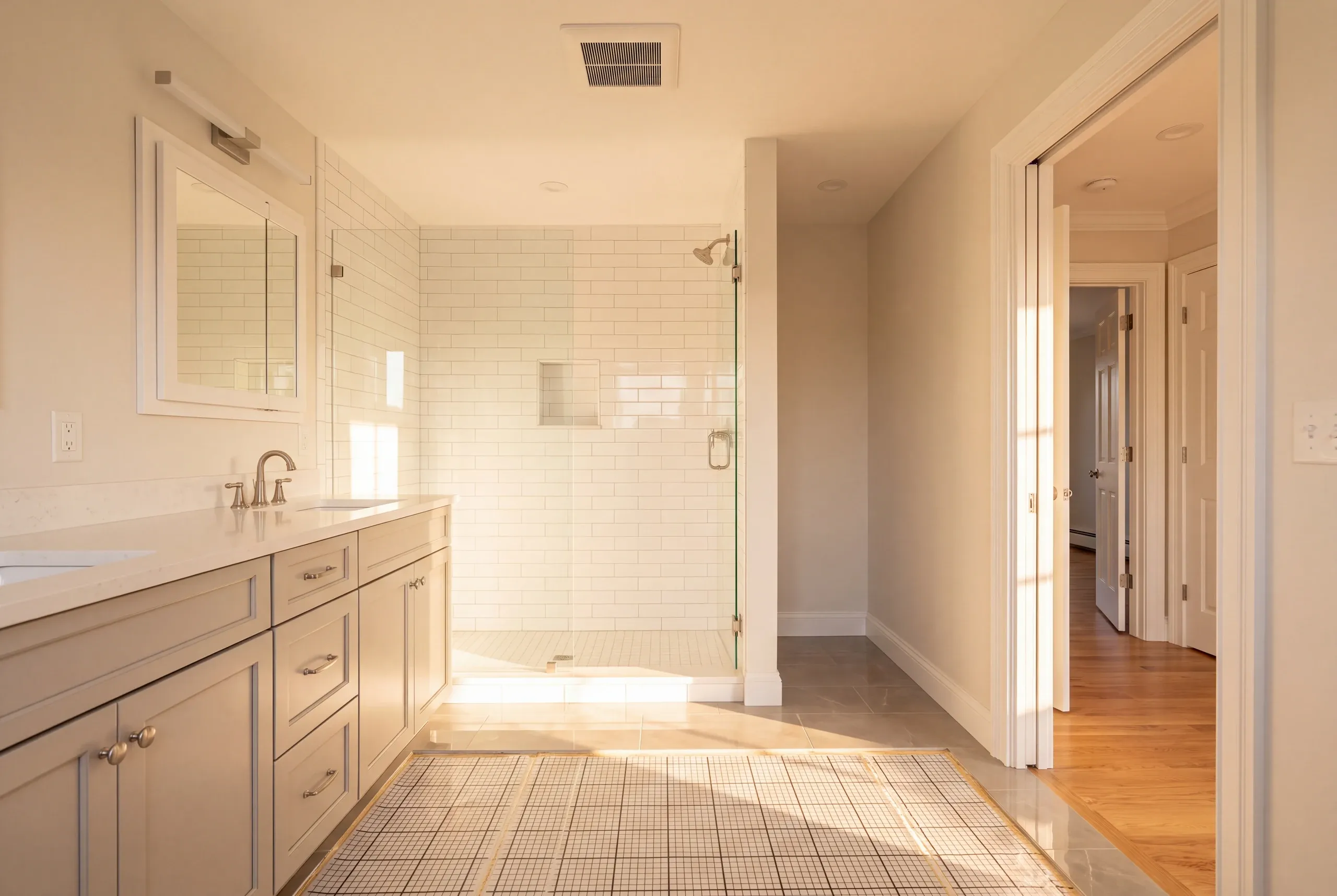 Bathroom remodeler Waldoboro Maine: white heating mat laid on the floor between a gray double vanity and subway tile shower