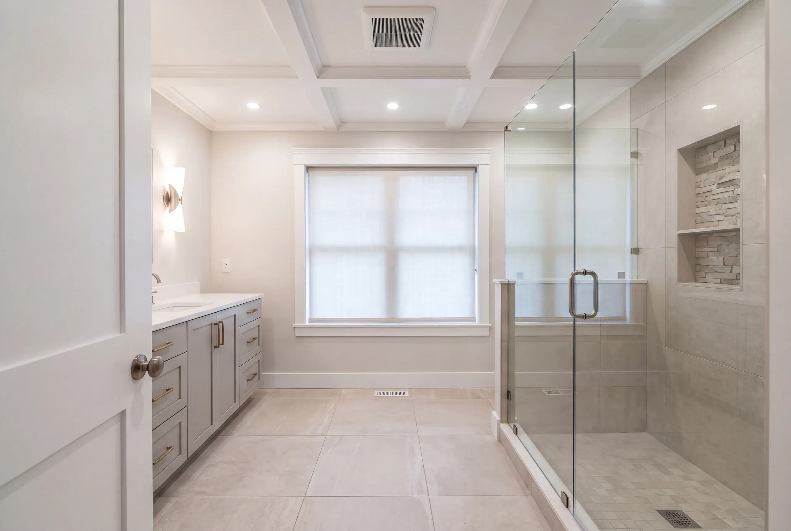 Bathroom remodeler Waldoboro Maine: coffered ceiling bathroom with a stacked stone niche in a glass shower and gray vanity