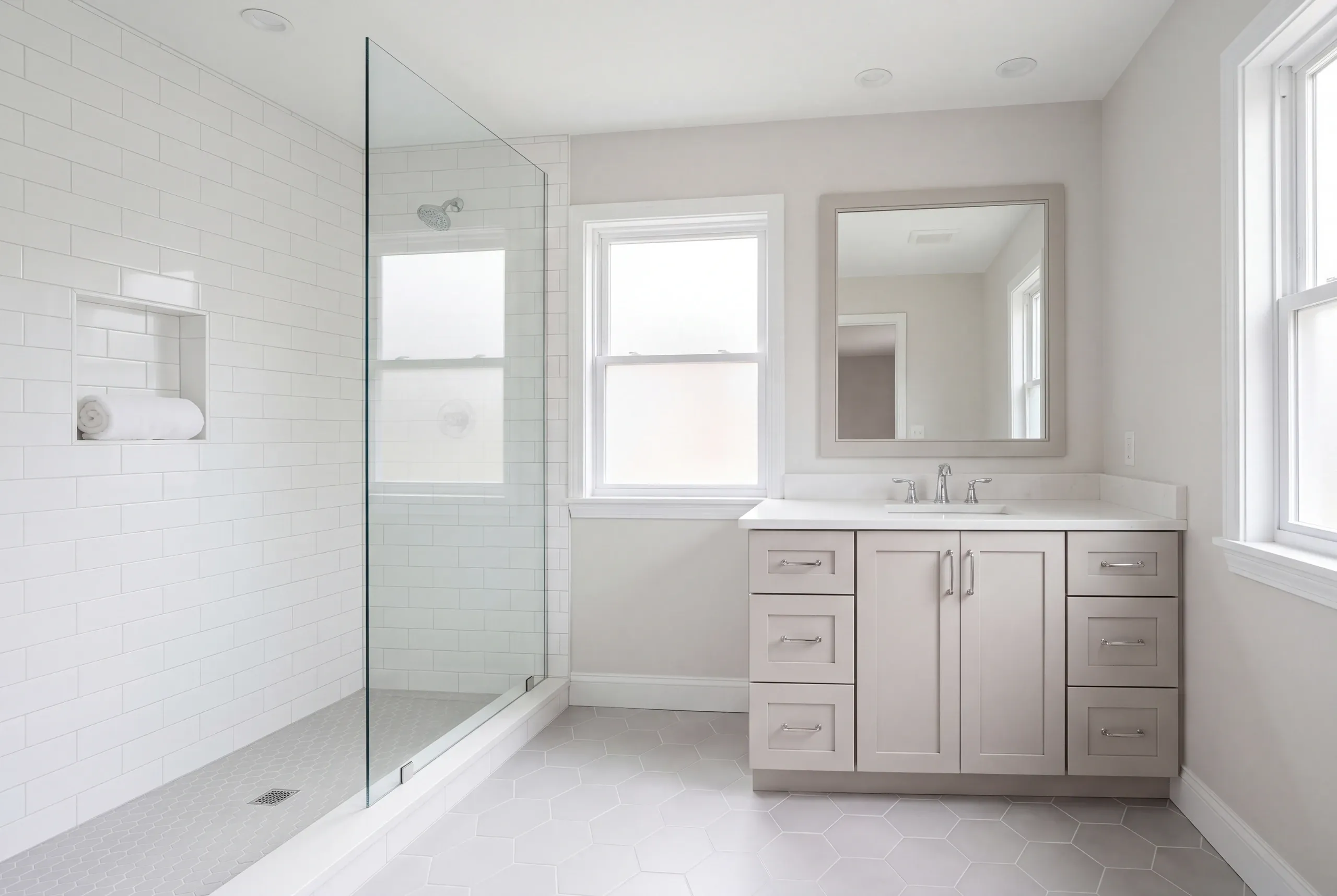 Bathroom remodeler Windsor Maine: subway tile shower with a towel niche and hex floor beside a gray shaker vanity