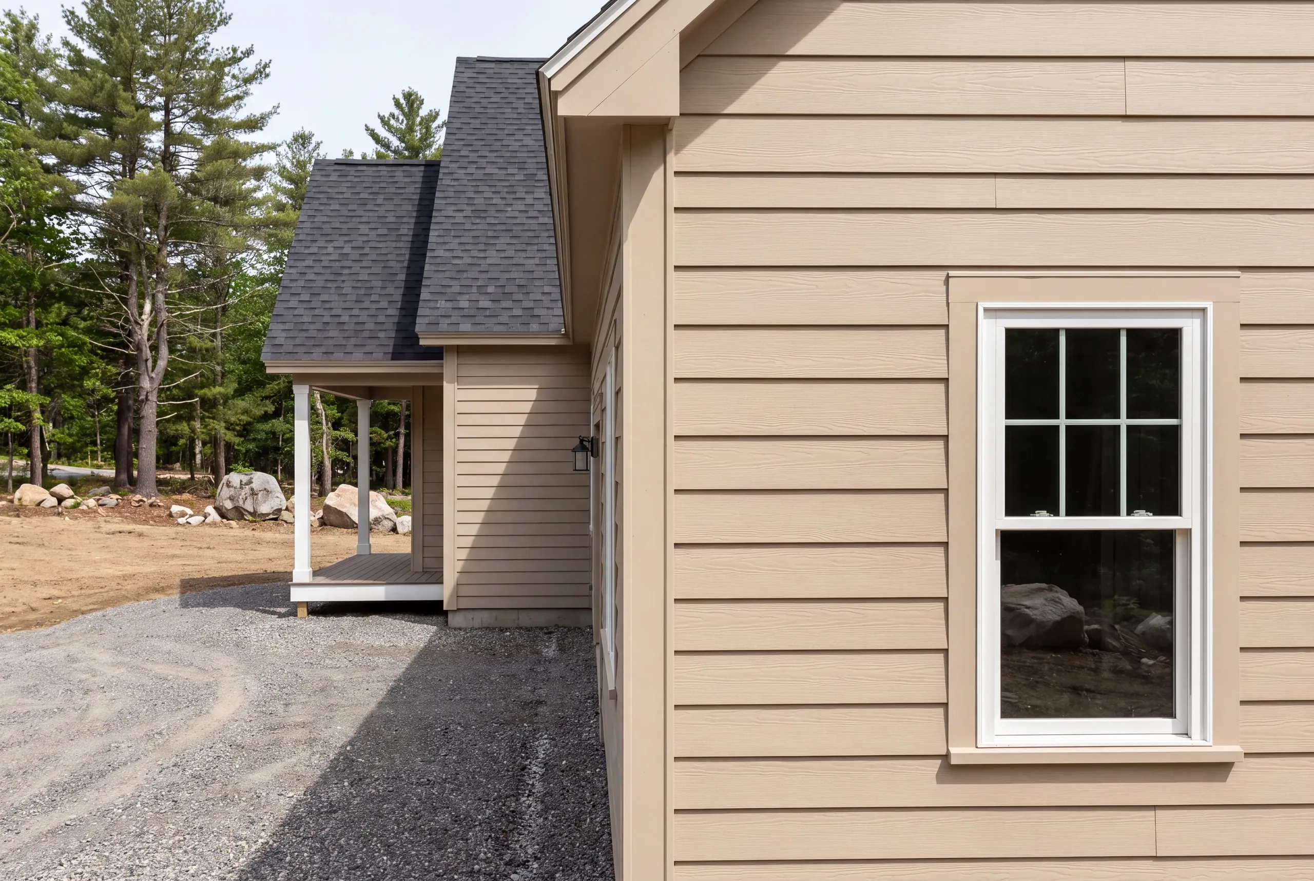 New home builder Damariscotta Maine: corner view of tan lap siding and a white double-hung window beside a small covered porch