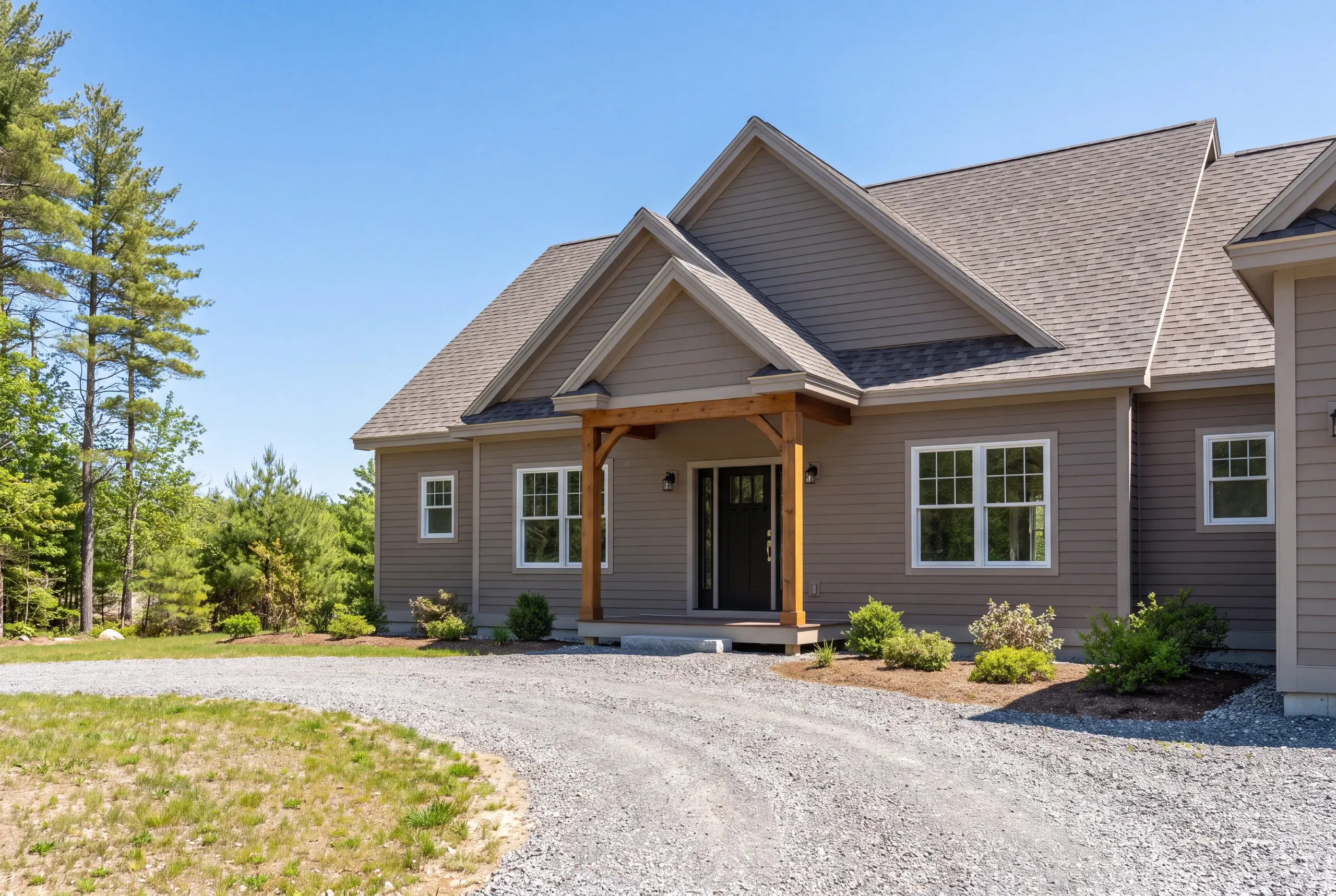 Residential home builder Gardiner Maine: taupe house with twin front gables, a timber post entry and a broad gravel turnaround