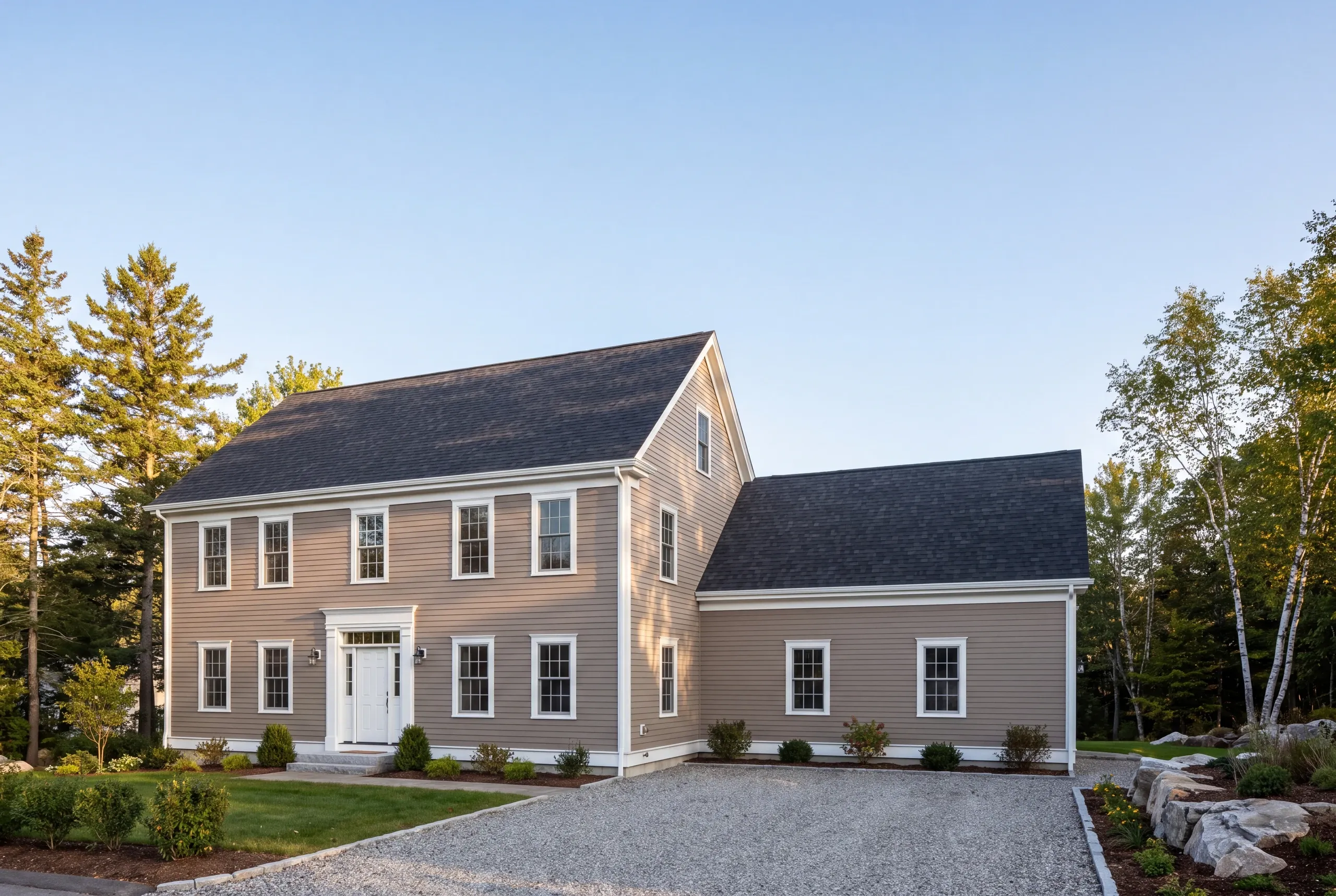 Construction company Camden Maine: tan two-story colonial with attached wing, gravel drive and birches