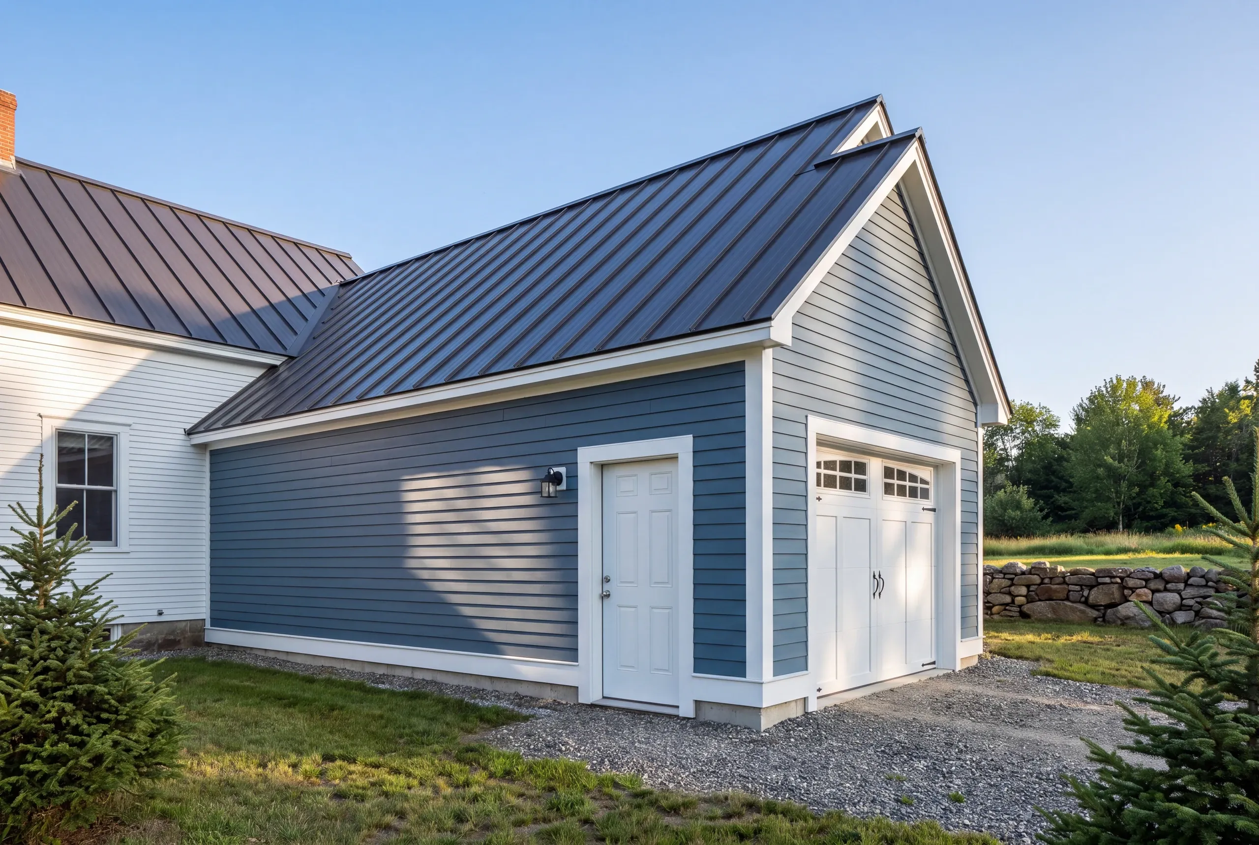 Residential general contractor Pittston Maine: blue lap-sided attached garage with a standing seam roof by a white farmhouse