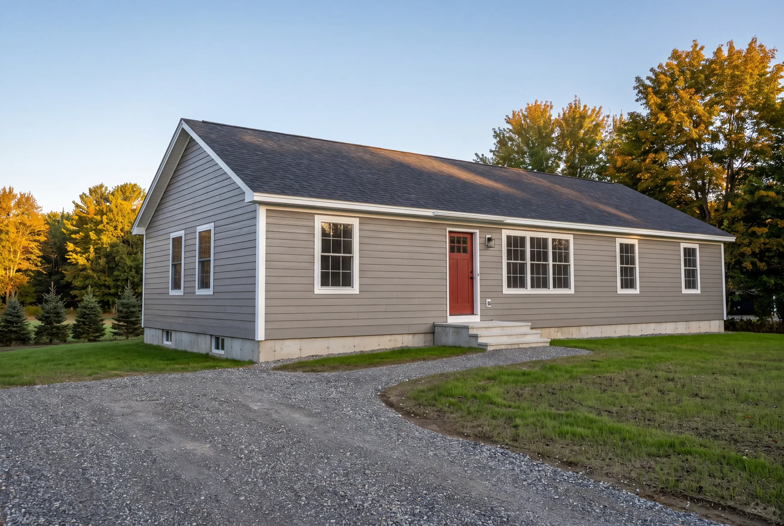 General contractor in Winslow, ME: single-story ranch with taupe lap siding, red front door and concrete steps on a new lawn