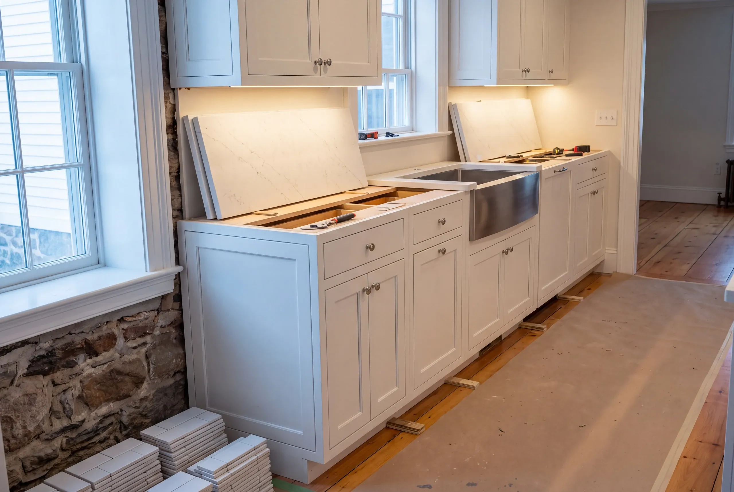 Kitchen remodeling contractor Bath Maine: white inset base cabinets on wood shims with counter slabs propped up and an apron sink in place