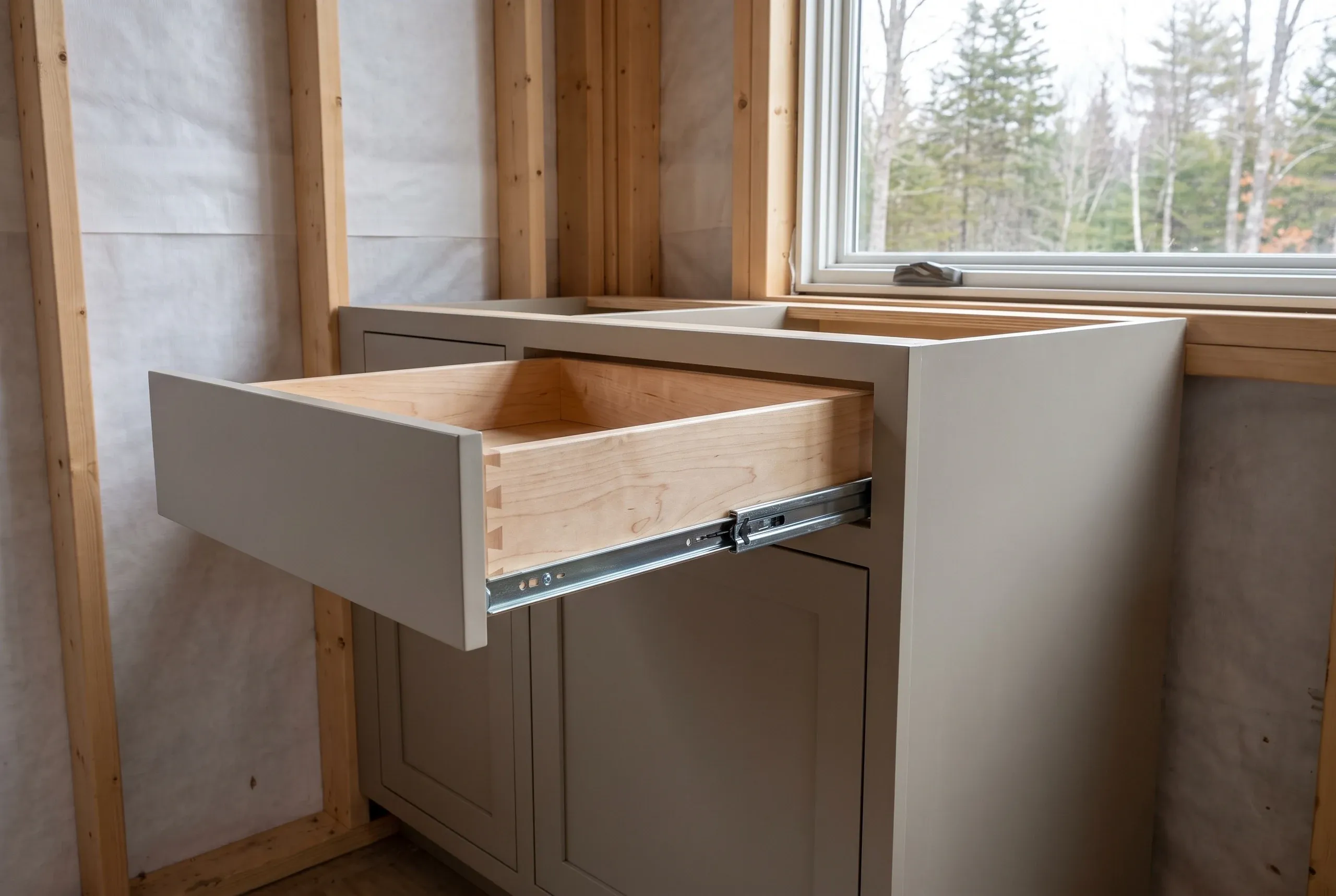 Kitchen remodeling contractor Belfast Maine: open dovetailed maple drawer on full-extension slides in a greige inset base cabinet
