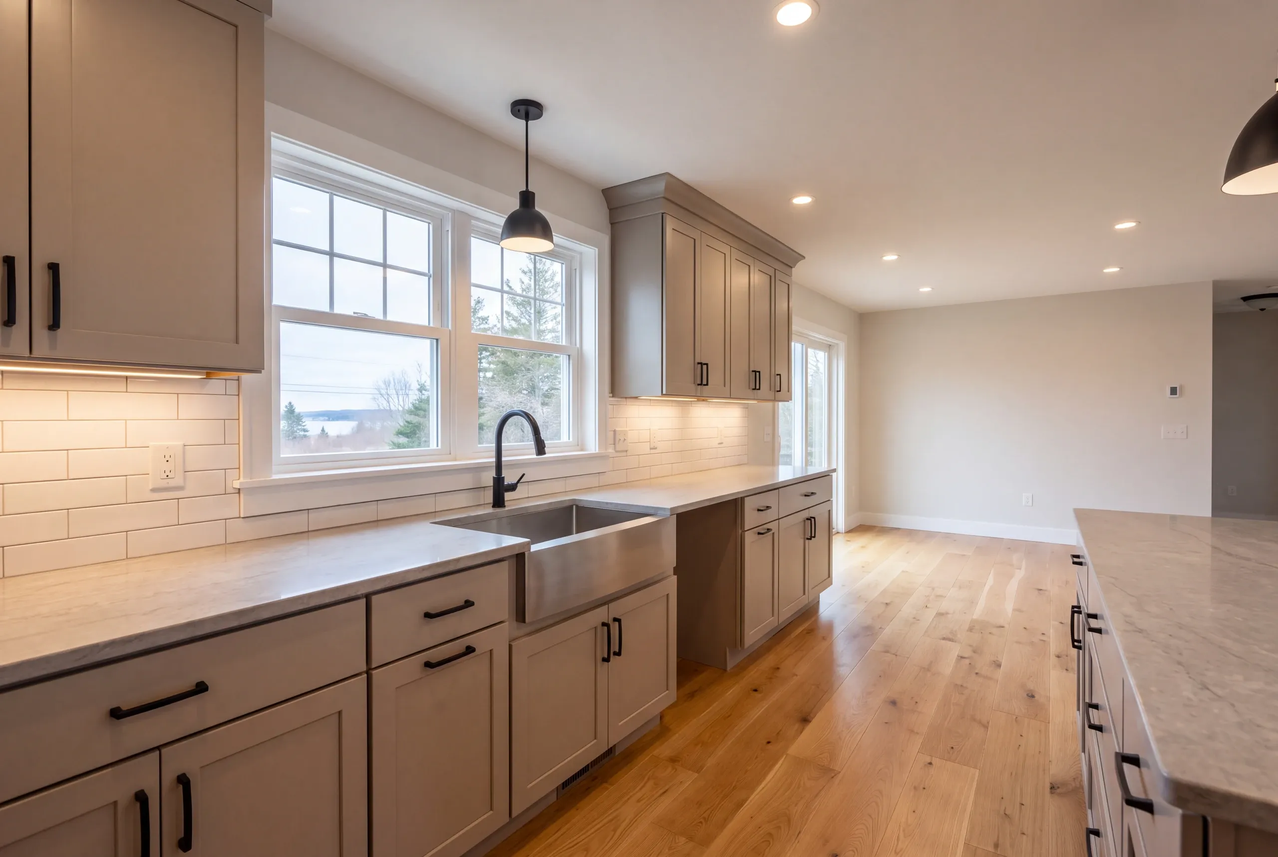 Kitchen renovation contractor Bucksport Maine: greige shaker cabinets with black pulls and a dome pendant over an apron sink