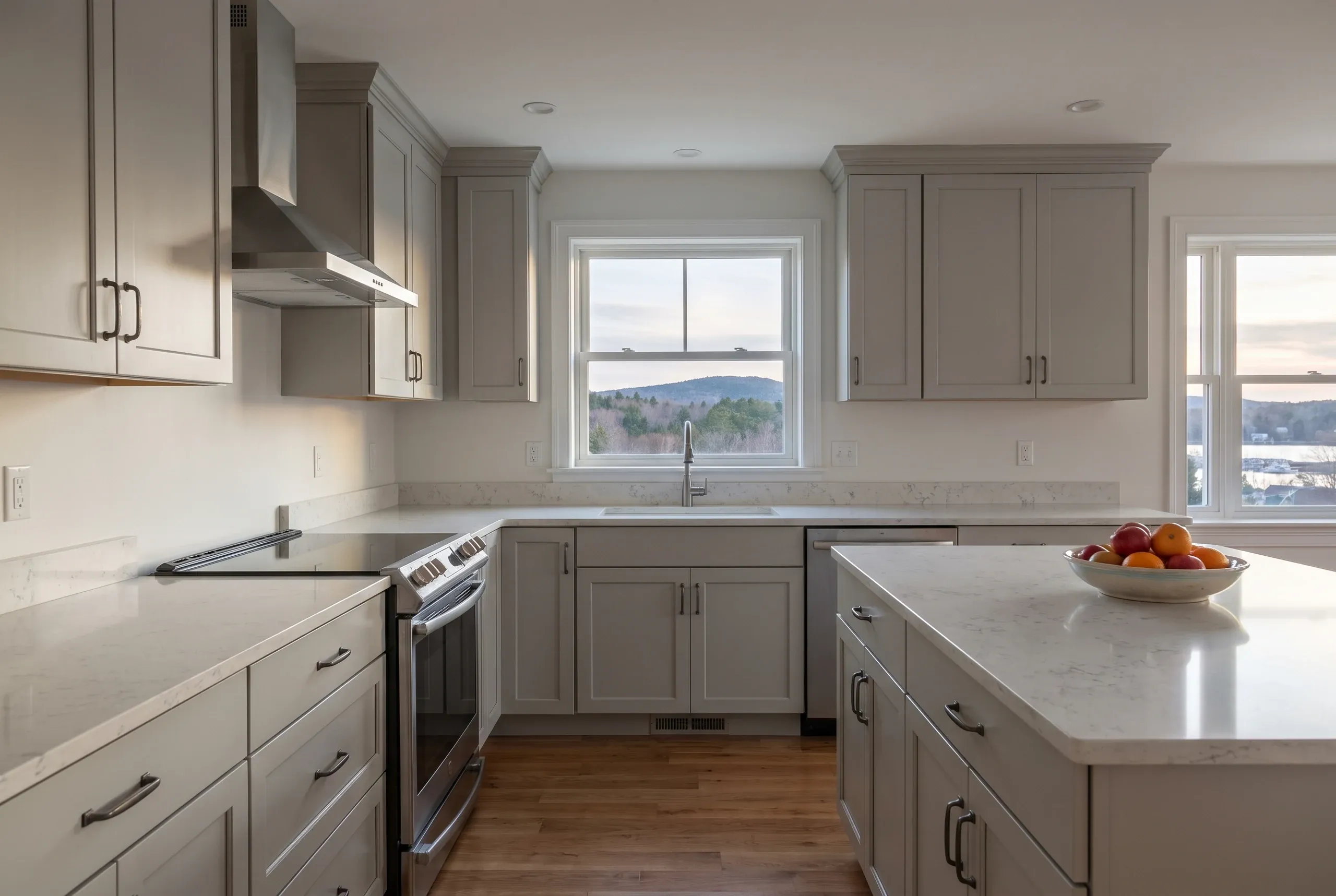 Kitchen remodeler Camden Maine: sage green shaker kitchen with a stainless chimney hood, slide-in range and a farmhouse apron sink.