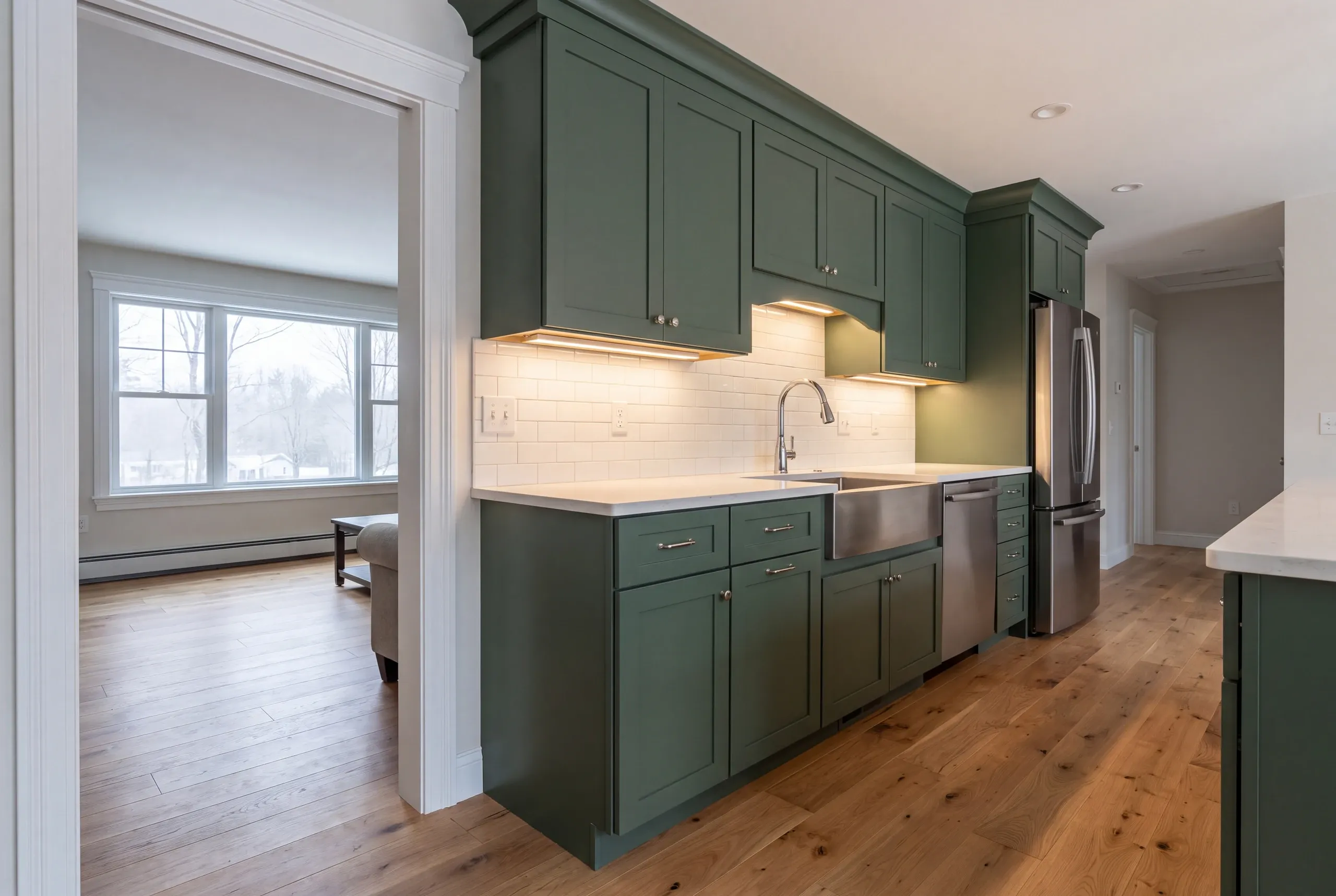 Kitchen remodeler Fairfield Maine: galley run of sage green shaker cabinets with a stainless apron sink and french-door refrigerator