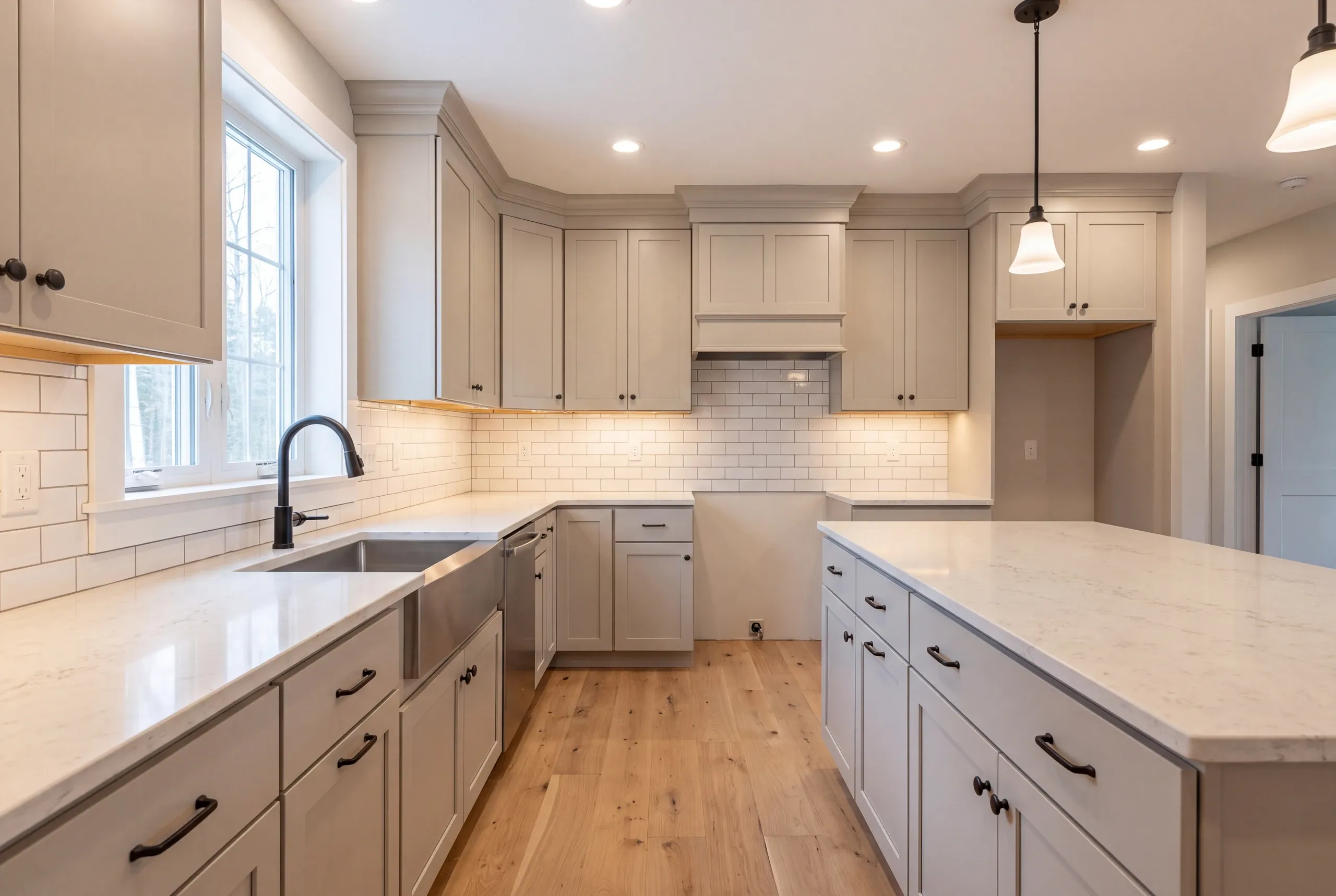 Kitchen renovation contractor Gardiner Maine: greige shaker kitchen with oil-rubbed bronze pulls, black faucet, apron sink and a wood hood box