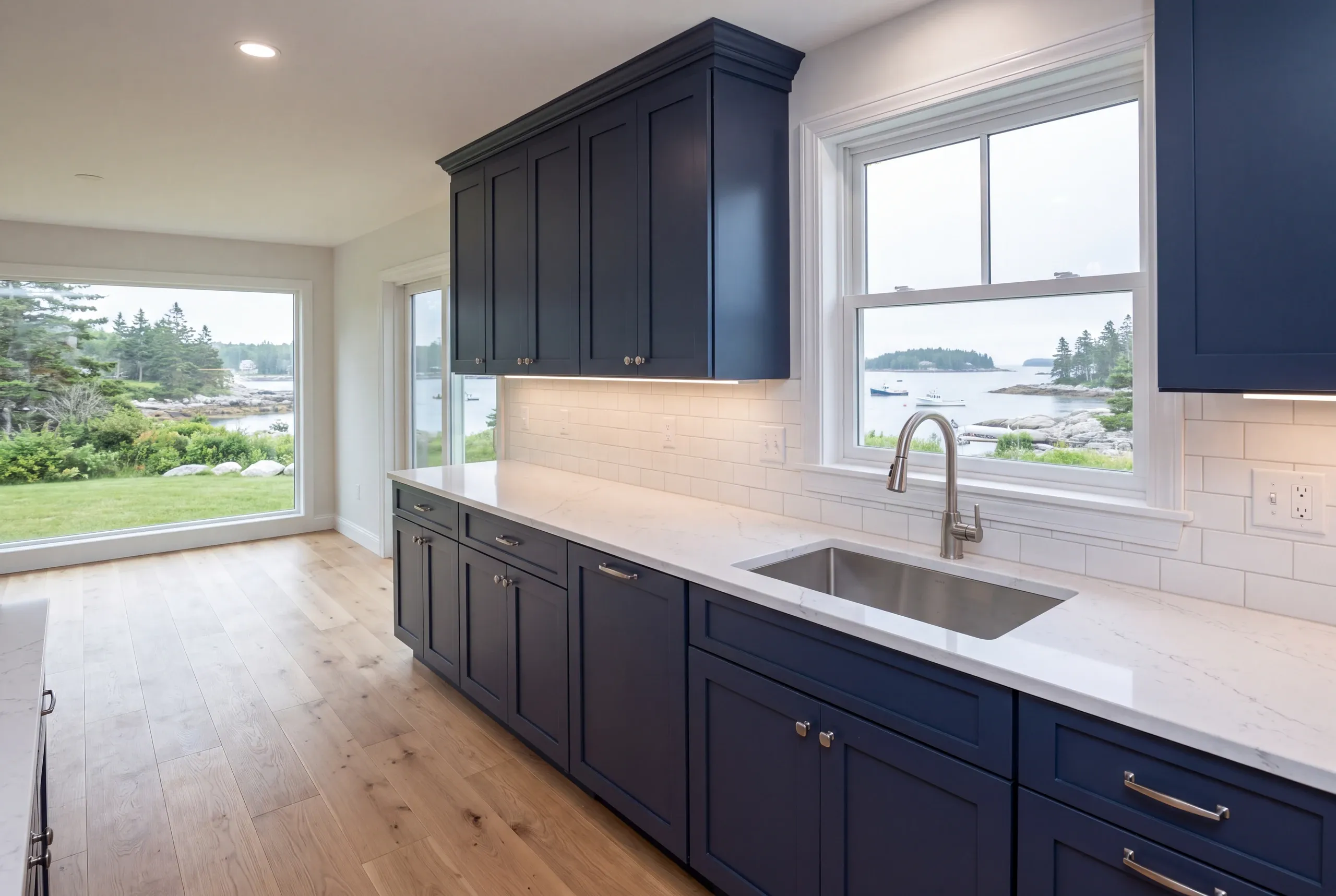 Kitchen remodeler Rockport Maine: navy shaker cabinets and an undermount sink at a window looking over a harbor with moored boats
