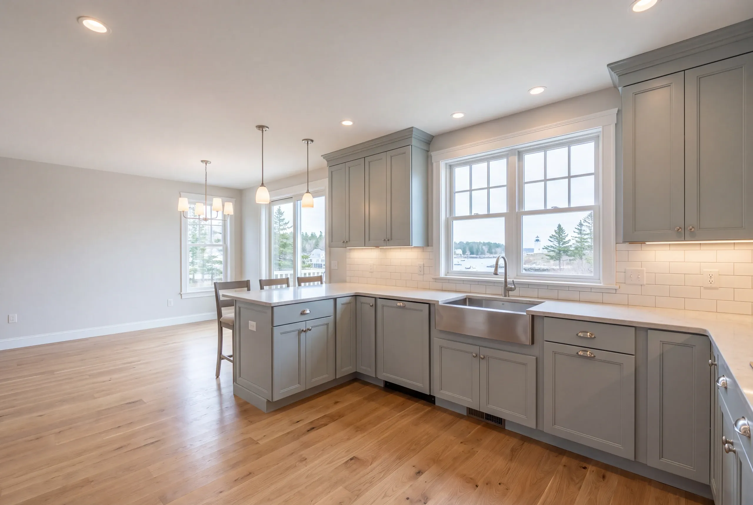 Kitchen remodeler Rockport Maine: blue-gray inset kitchen with a peninsula, stainless apron sink and a lighthouse view out the window