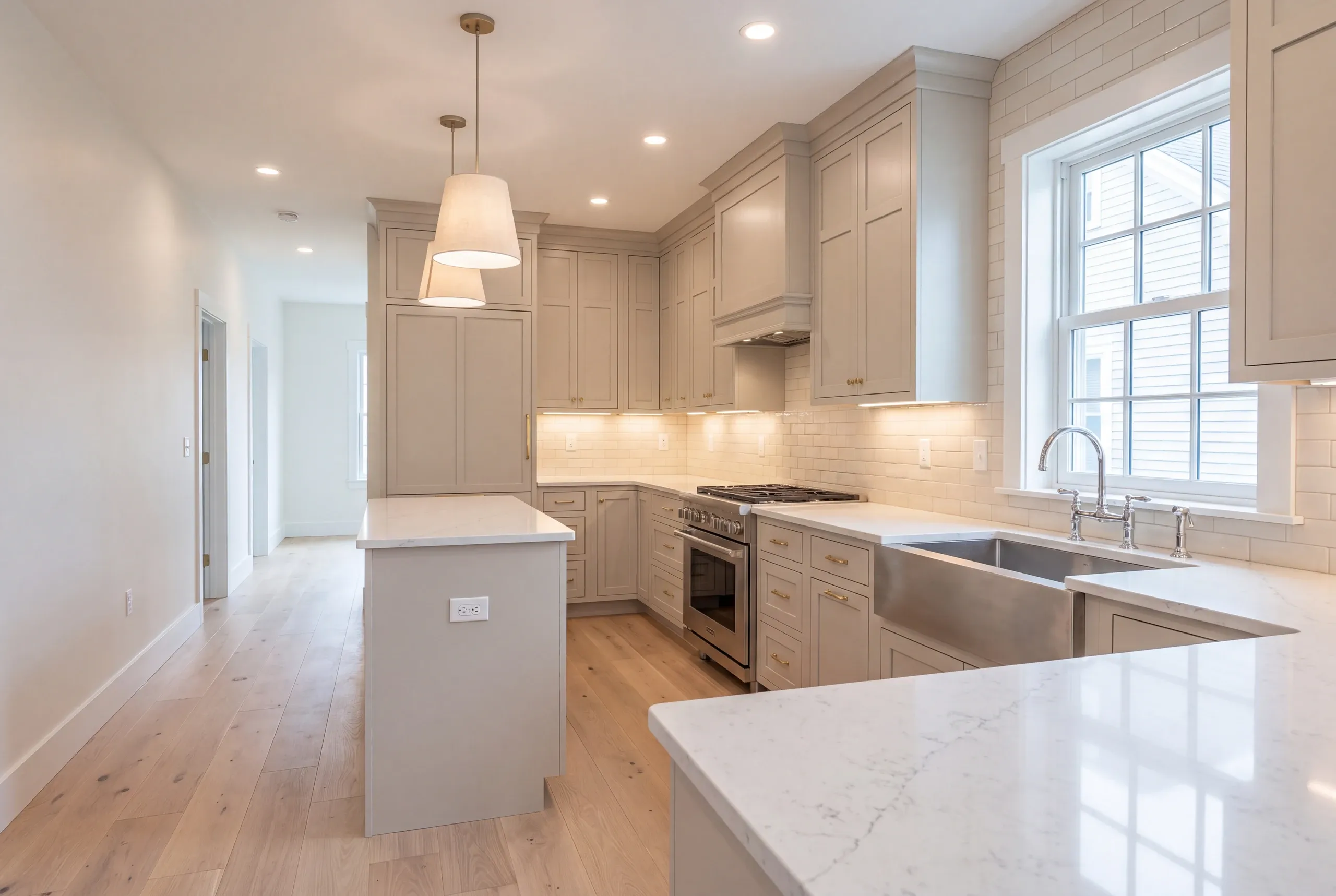 Kitchen remodeler Waterville Maine: greige kitchen with drum pendants, a stainless range and a steel apron sink