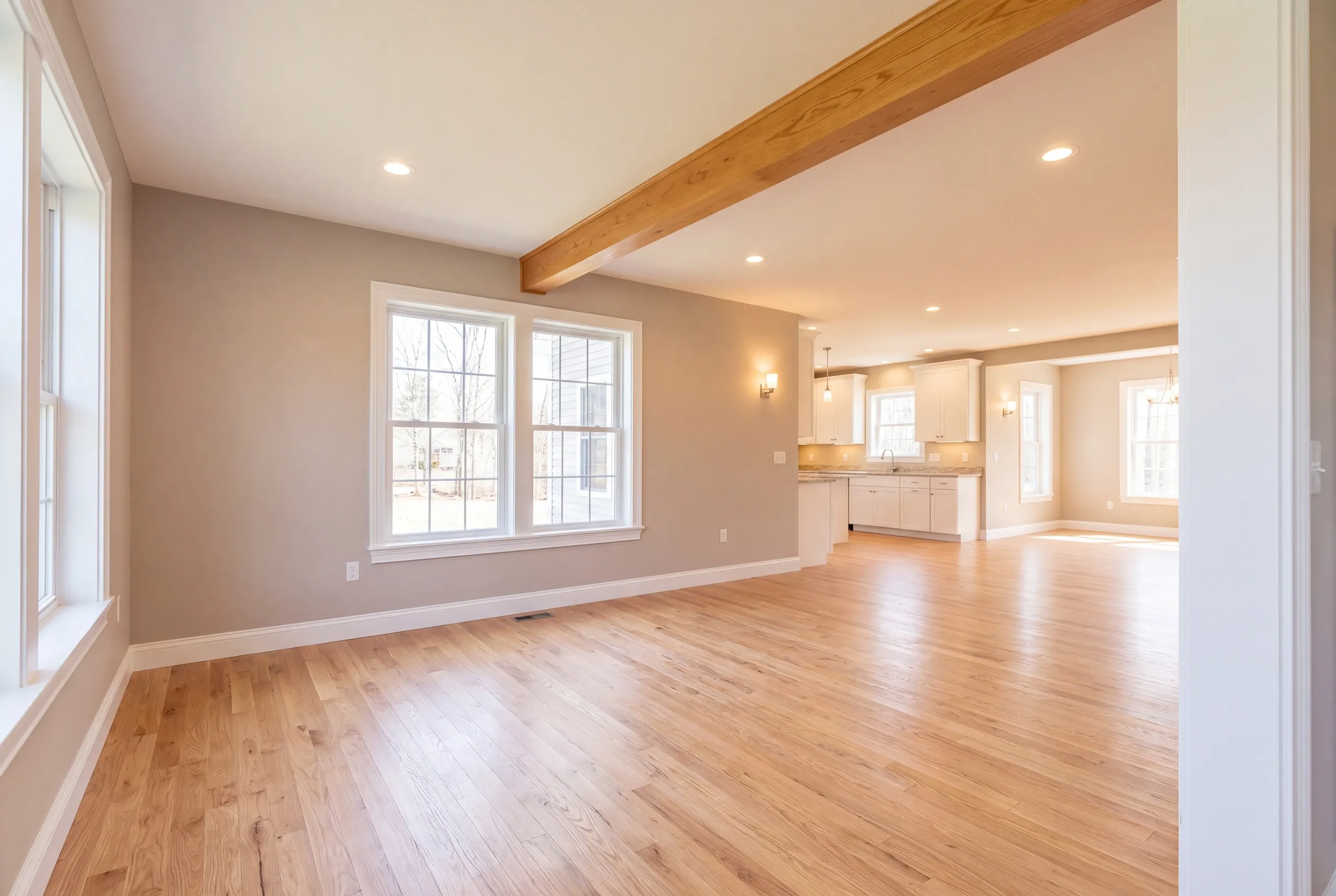 Remodeling company Augusta Maine: open living room with a natural beam leading to a white kitchen at the back