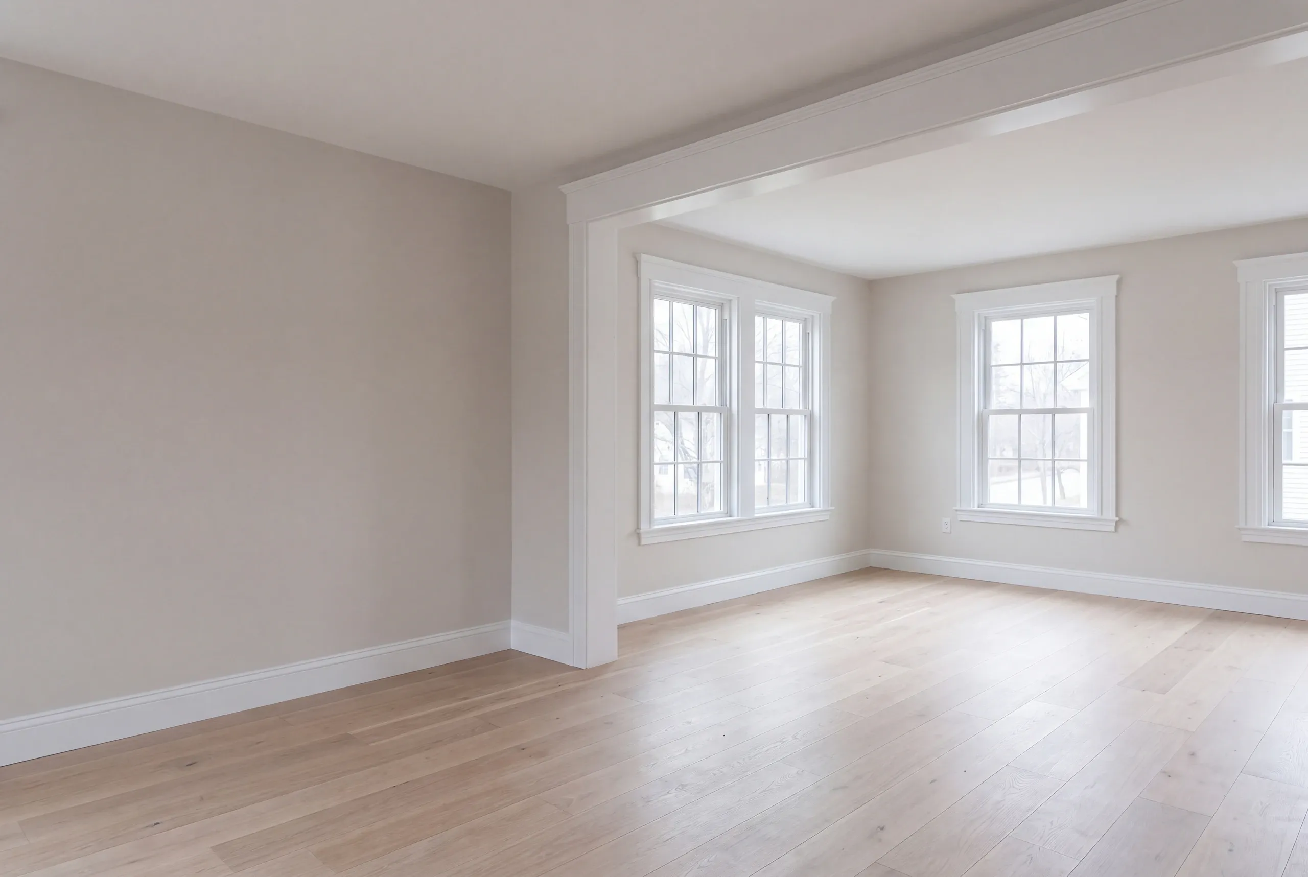 Remodeling company Bath Maine: empty white room with a wide cased opening into a bright corner room