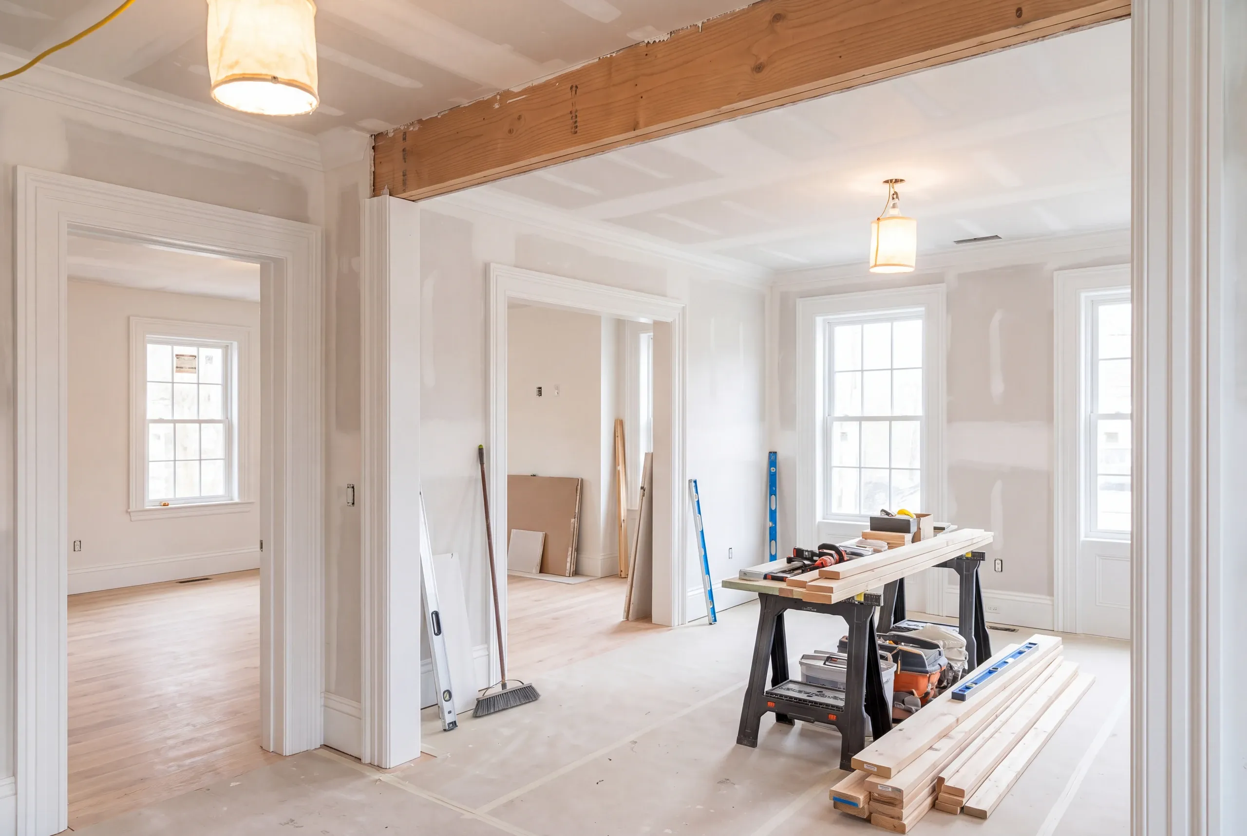 Home remodeling contractor Belfast Maine: renovation in progress with taped drywall, a new beam, sawhorses and lumber