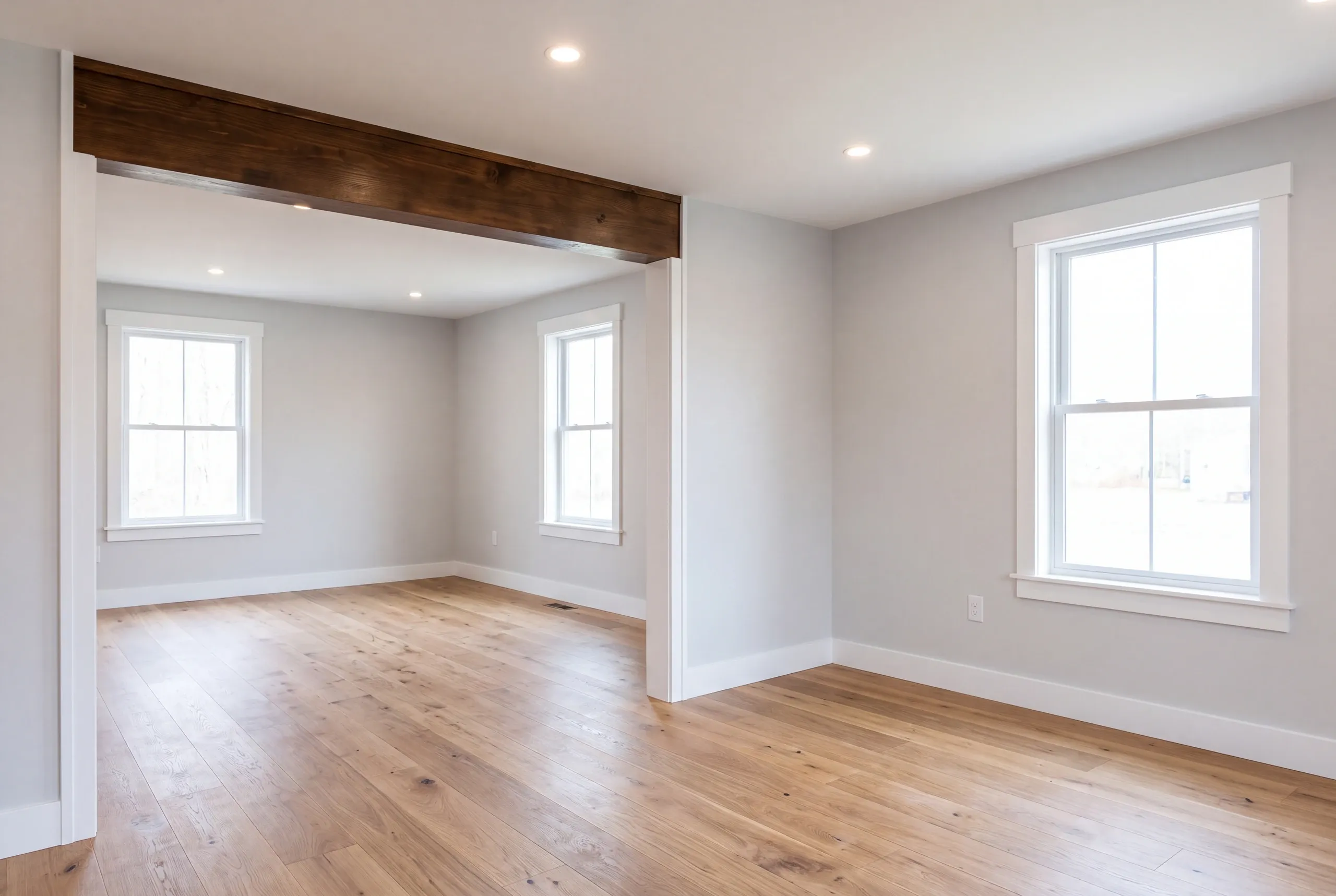 Home renovation contractor Bucksport Maine: gray-walled rooms joined under a dark timber beam with two double-hung windows