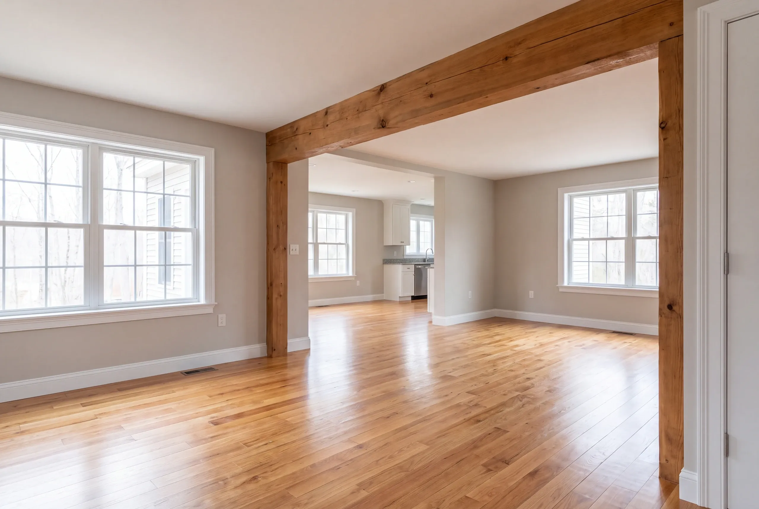 Home renovation contractor Bucksport Maine: open living space under a rough timber post and beam with a kitchen beyond