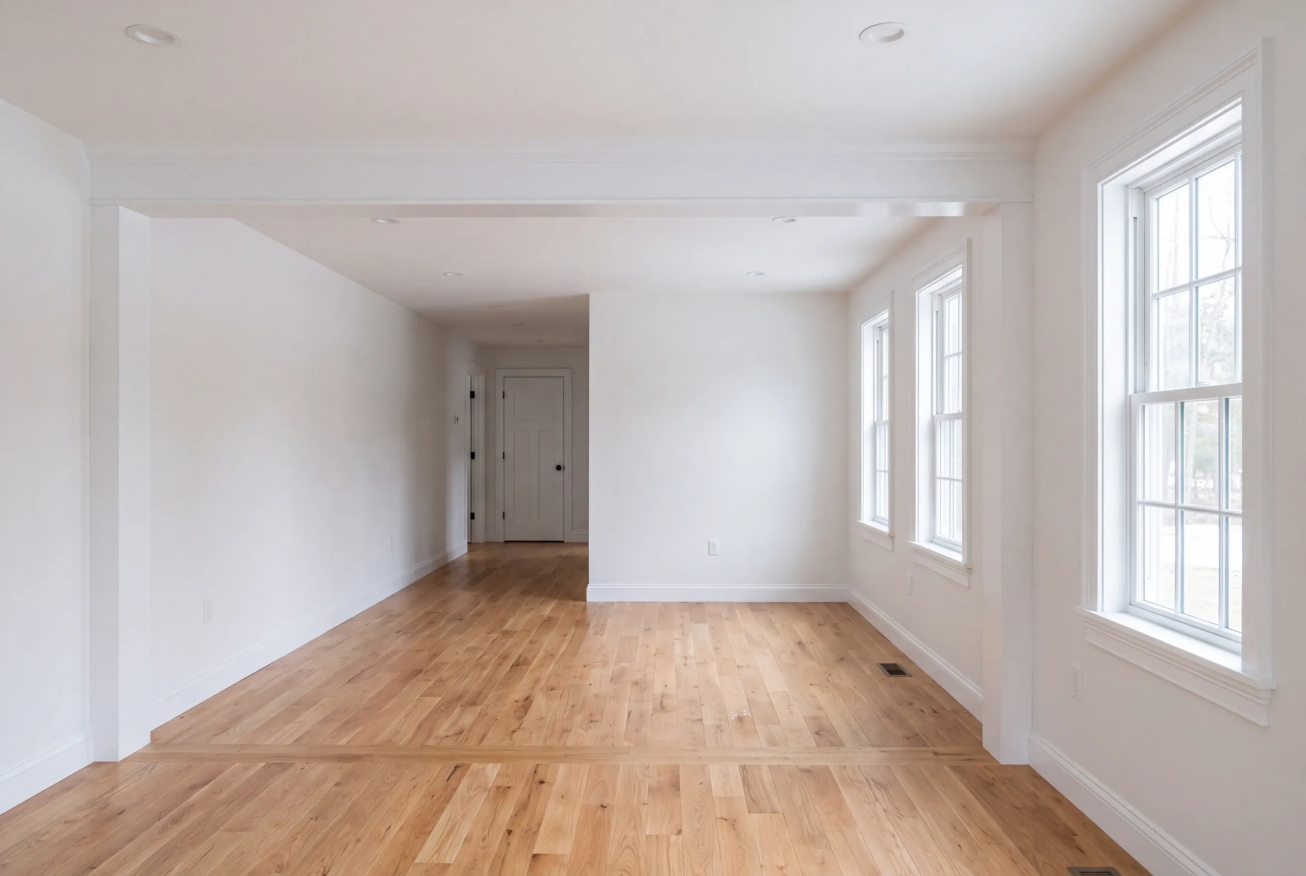 Remodeling company Bucksport Maine: long empty room with white trim and a hallway door at the far end