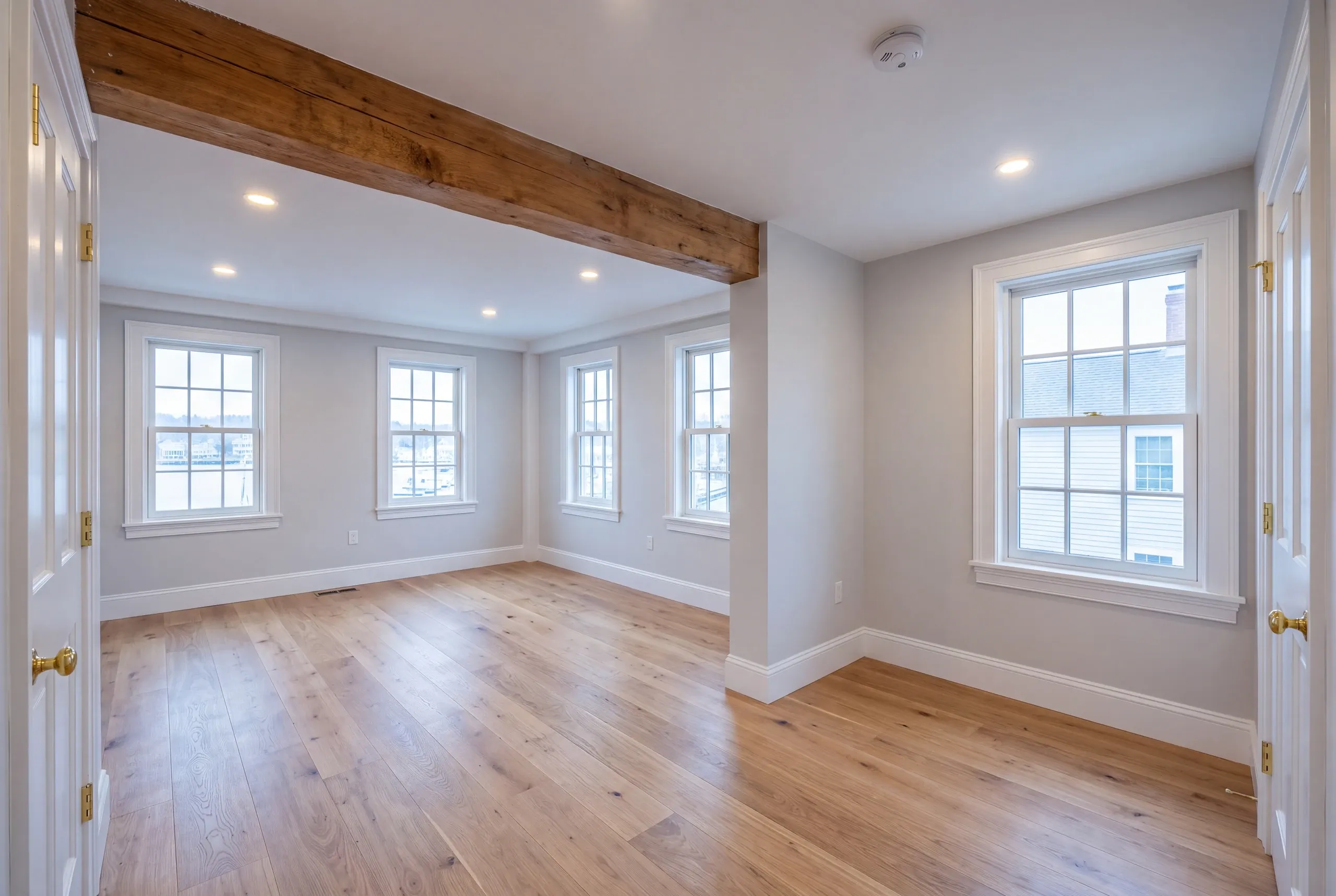 Home renovation contractor Camden Maine: two empty rooms joined under a rough wood beam with French doors open