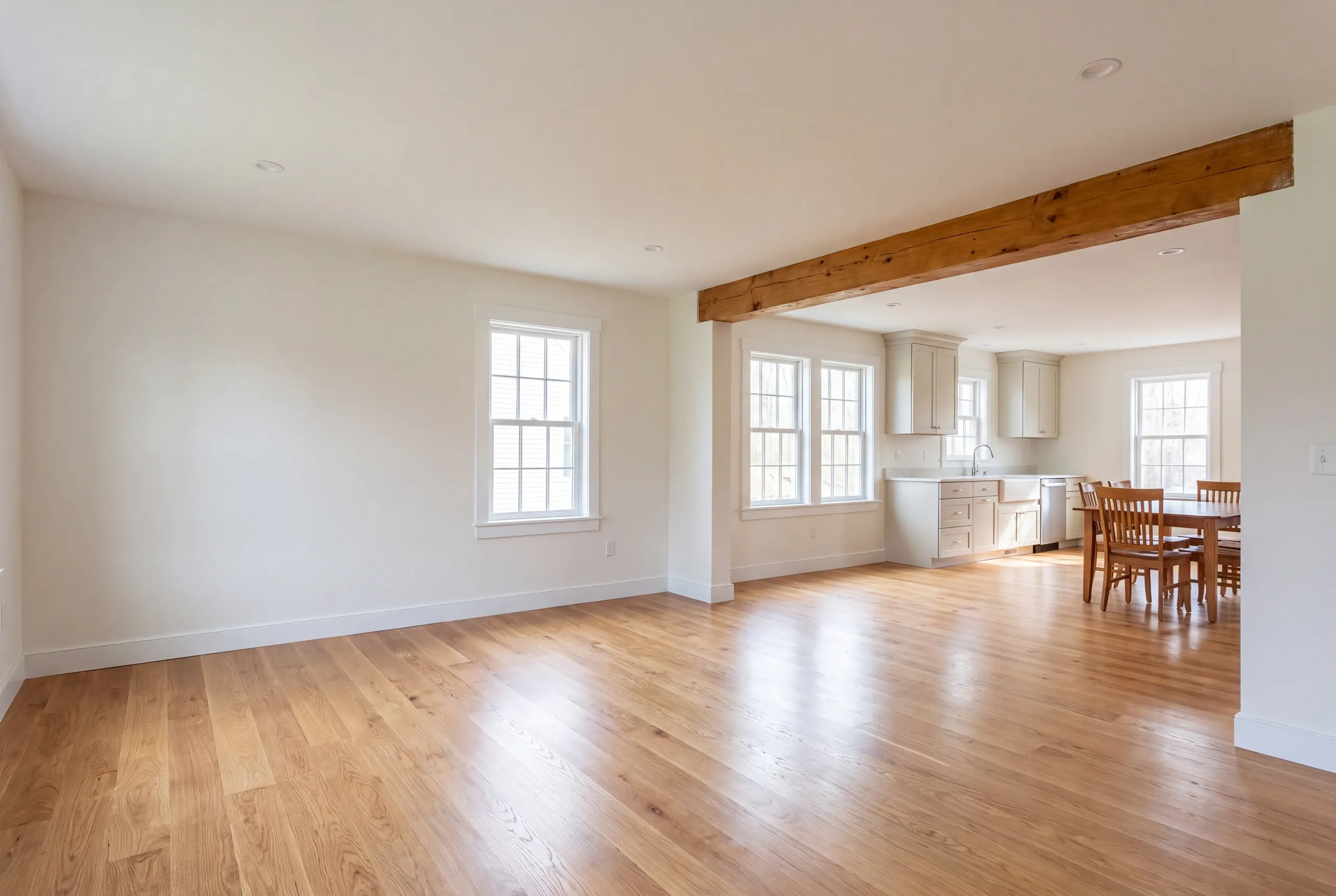 Remodeling company Camden Maine: empty living room with a natural beam opening to a kitchen and dining table