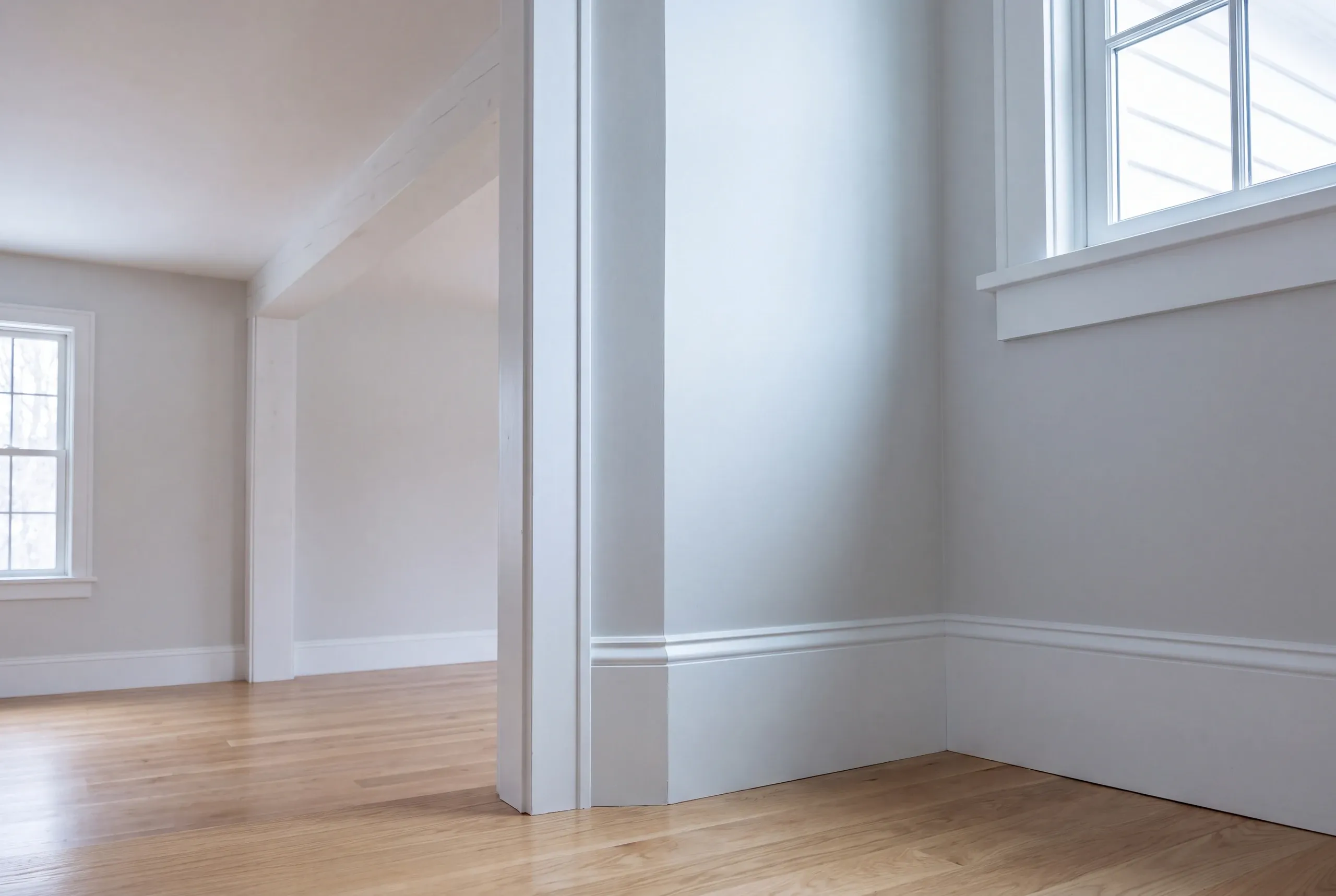 Home renovation contractor Damariscotta Maine: empty white room corner with a wide cased opening and deep window trim