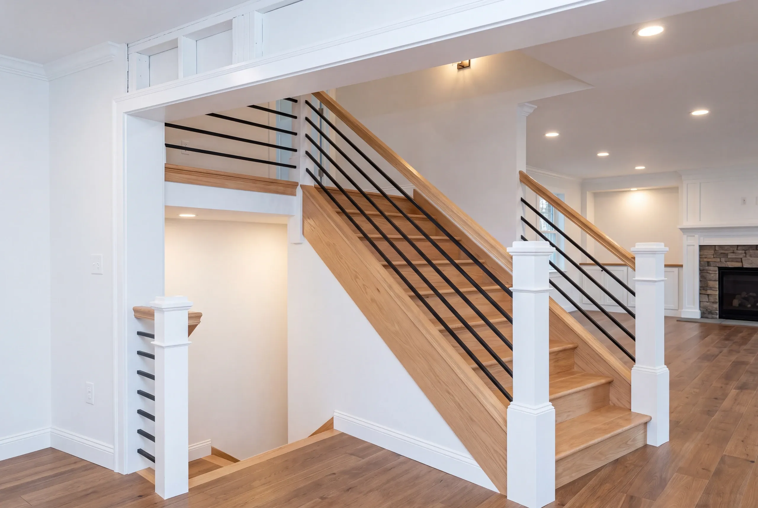 Home renovation contractor Fairfield Maine: split-level stair with oak treads, white newels and black horizontal metal rails