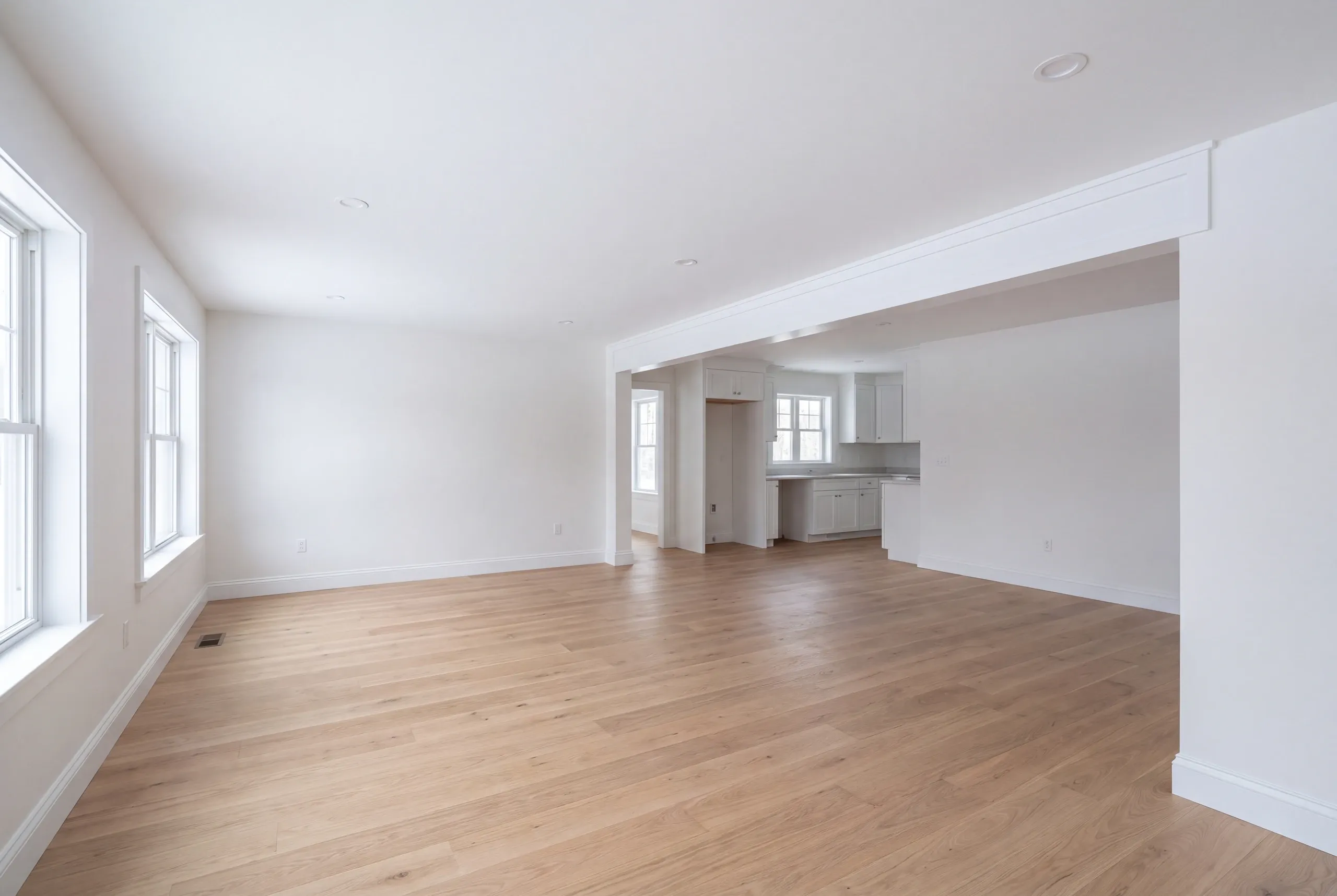 Remodeling company Fairfield Maine: empty open room with a cased opening through to a kitchen at the back