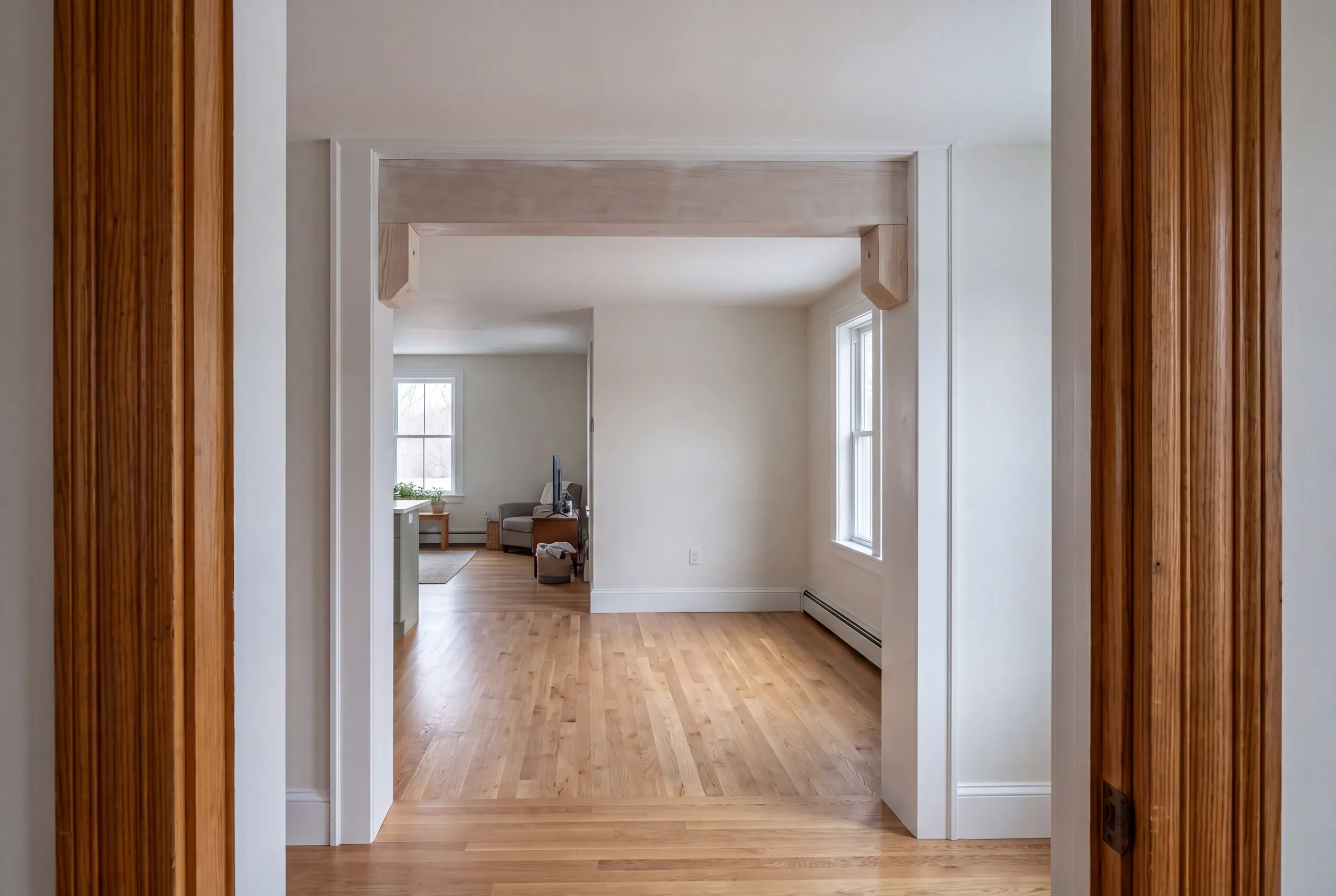 Home remodeling contractor Pittsfield Maine: view through dark fir door casings to a whitewashed beam with corbels and a living room