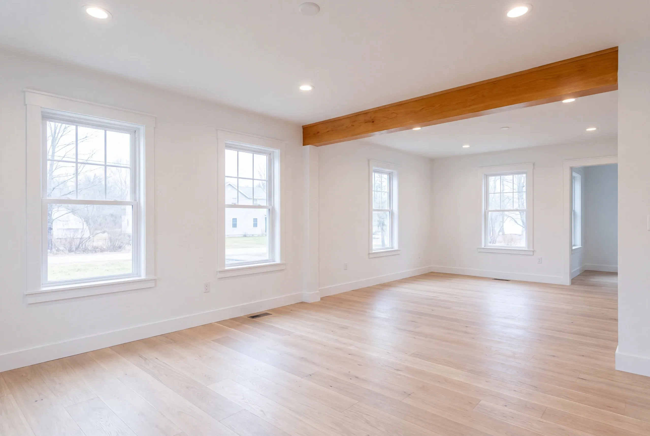 Home renovation contractor Pittsfield Maine: empty room with a natural beam and double-hung windows on three walls