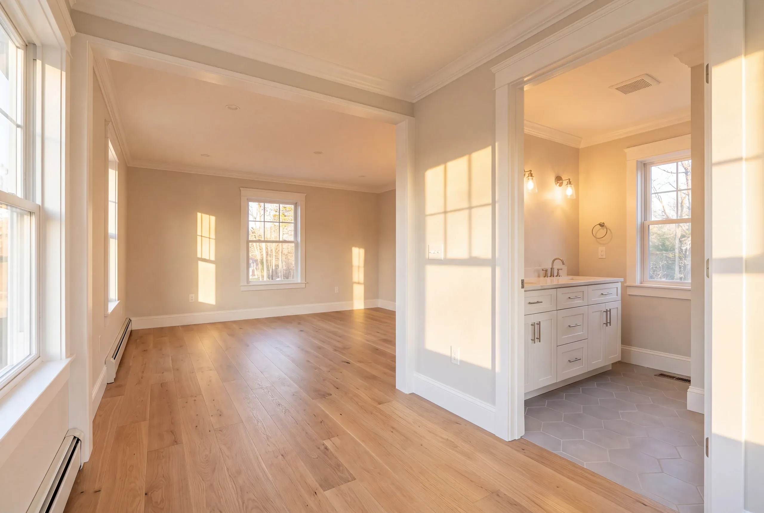 Home remodeling in Pittston, ME: sunlit room opening into a bathroom with a white vanity, sconces and hex tile floor