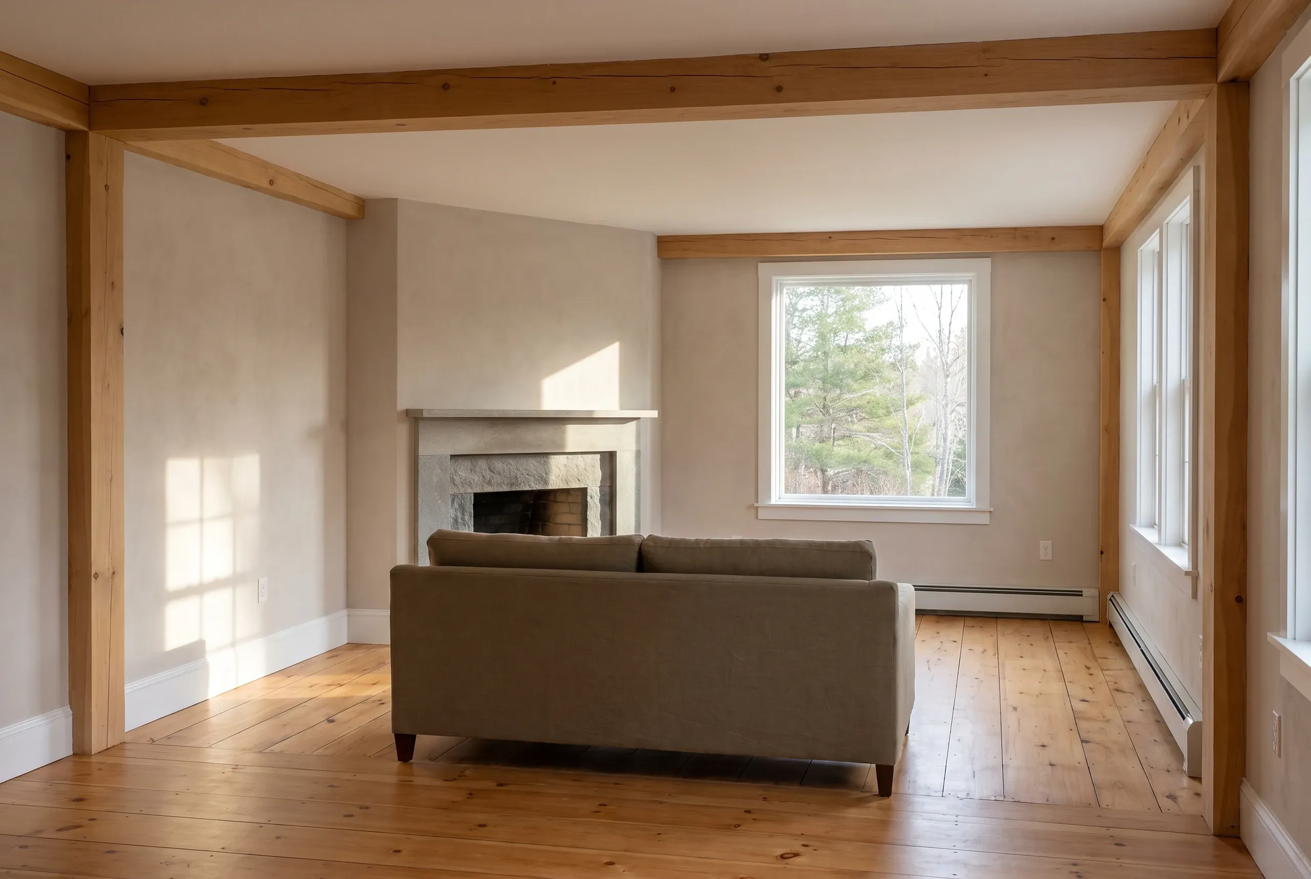 Remodeling company Pittston Maine: remodeled sitting room with a woodstove on a tile pad, tall window and refinished pine plank floor.