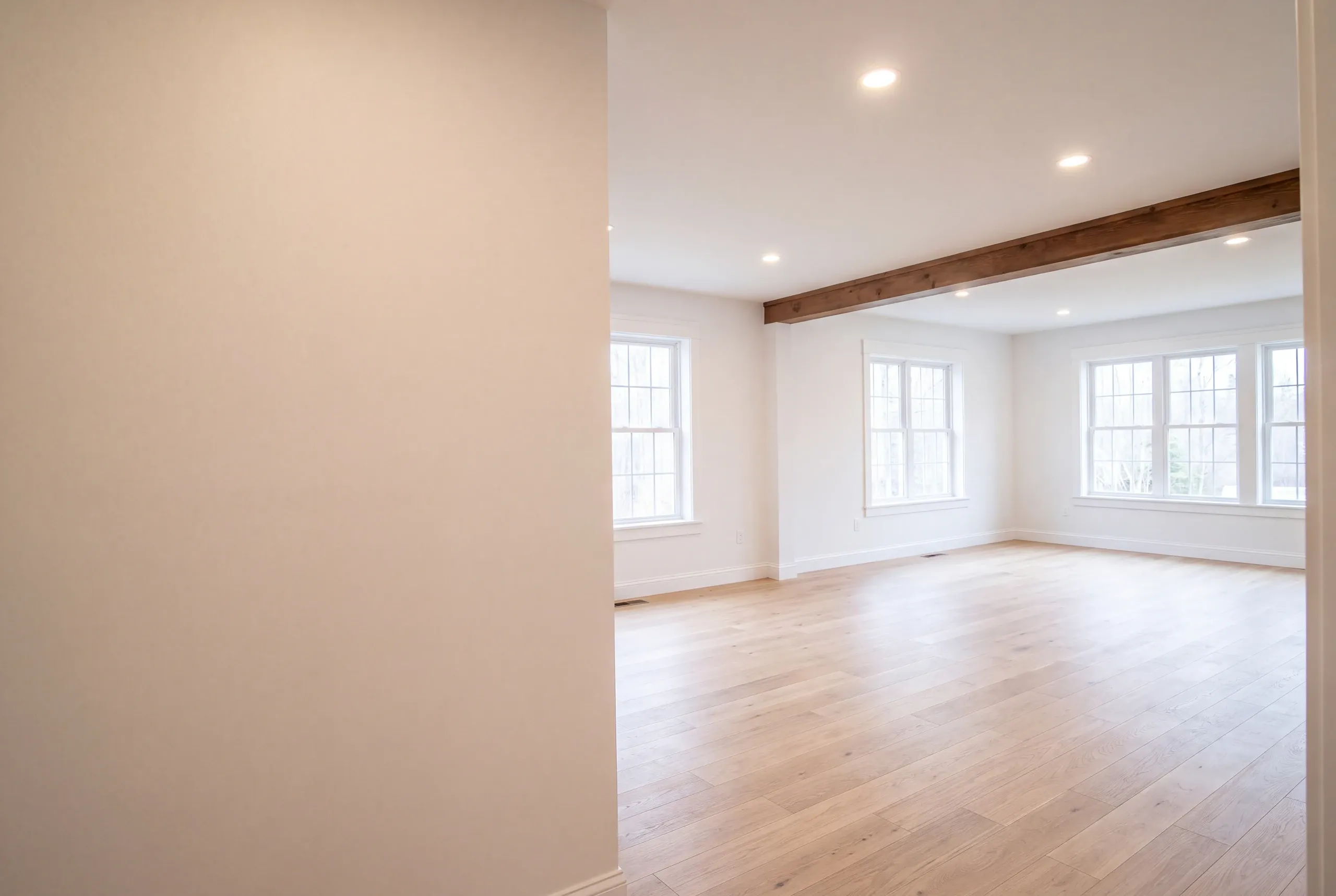 Remodeling company Pittston Maine: empty room with a stained beam and banks of windows on two walls