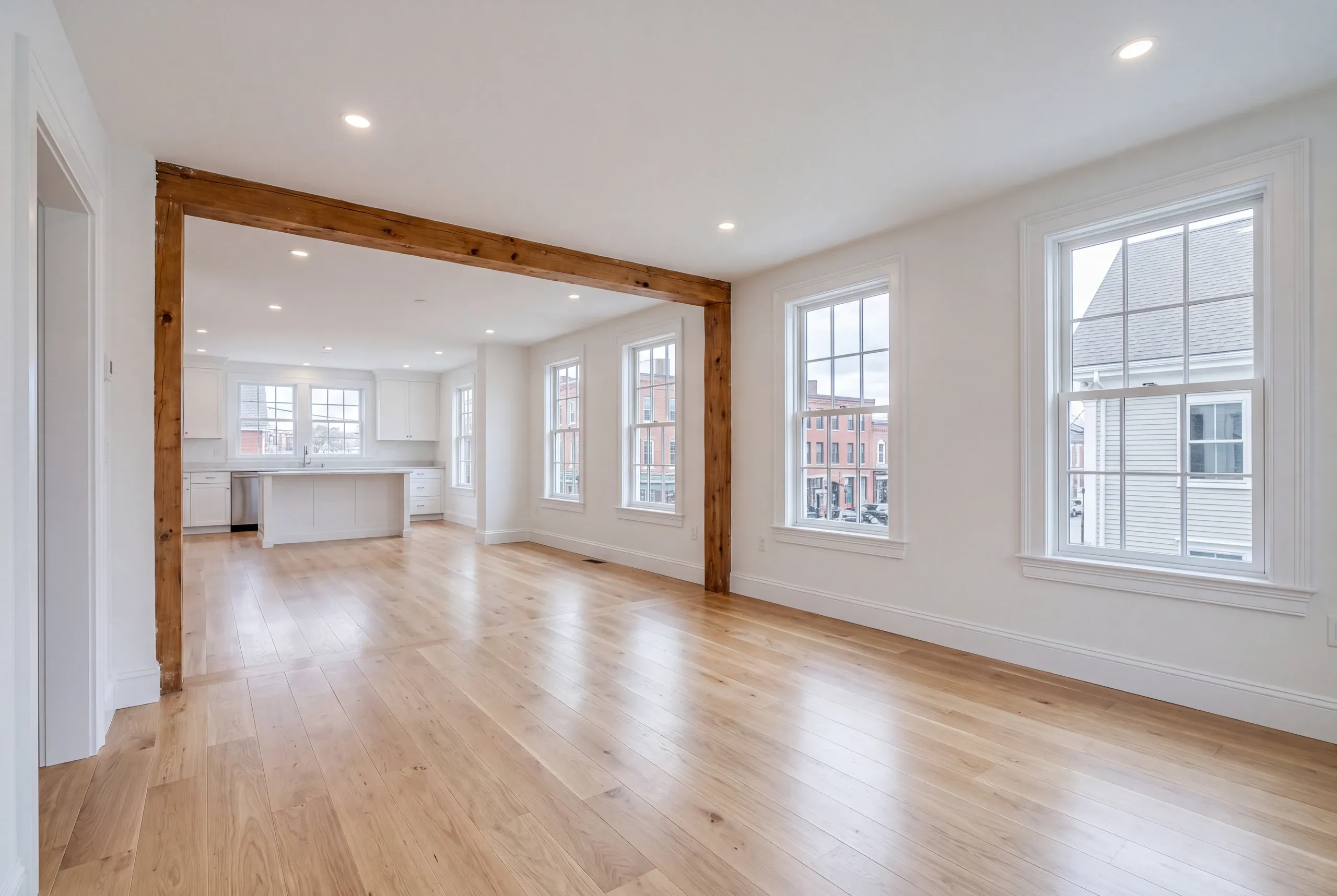 Remodeling company Rockland Maine: open main floor with a timber post and beam, kitchen island and brick buildings outside