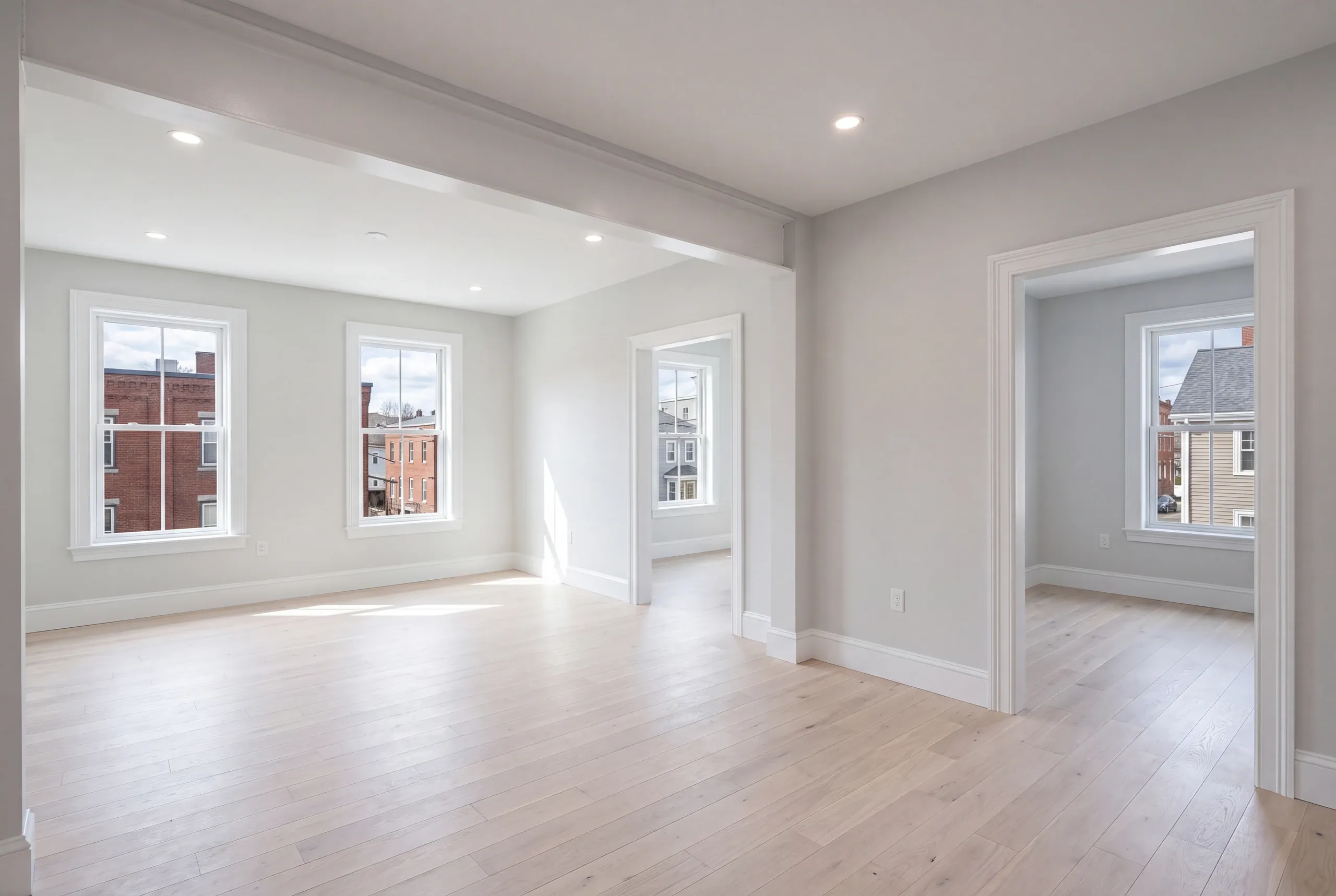 Home renovation contractor Rockland Maine: empty rooms with gray walls and windows facing brick buildings next door