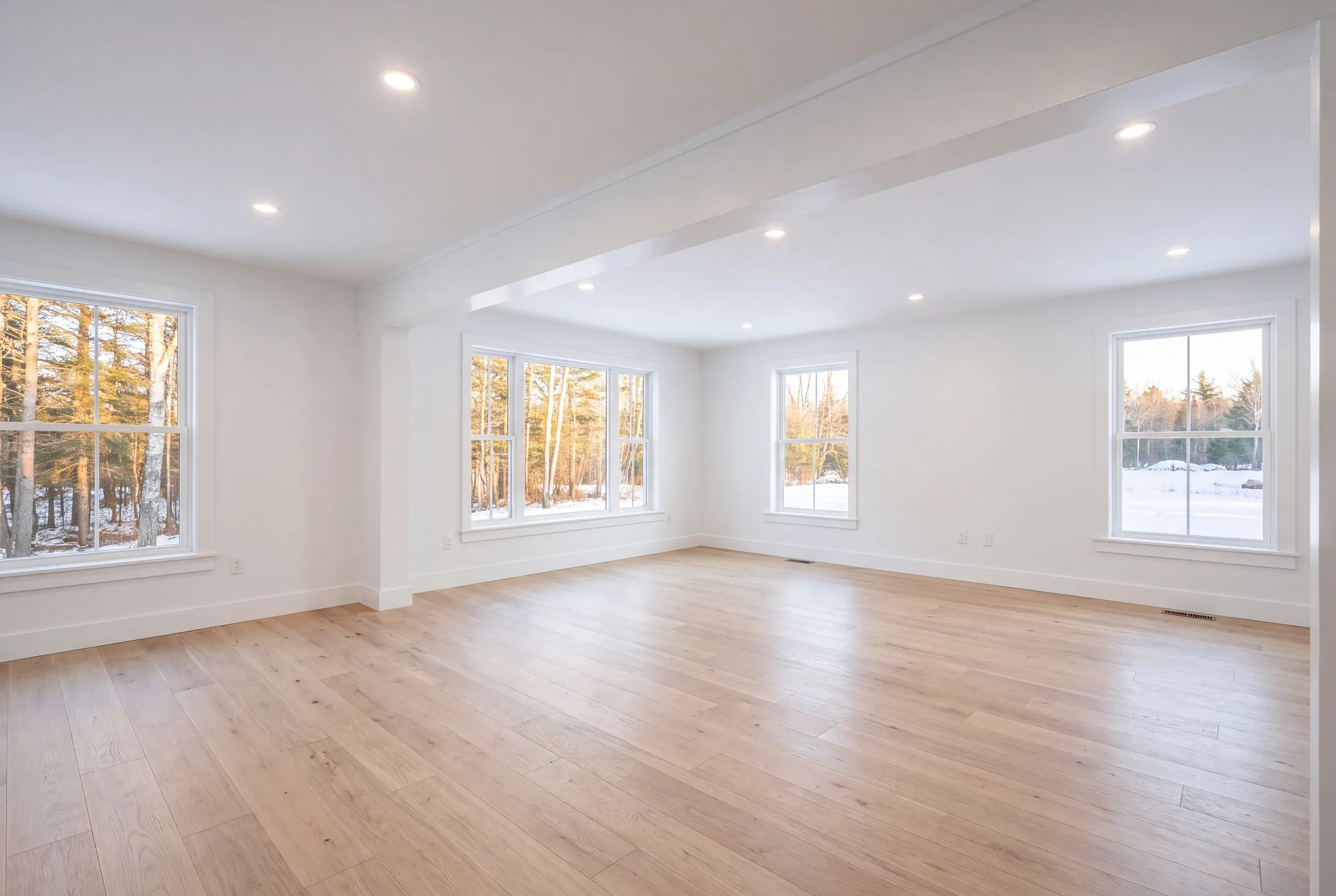 Remodeling company Searsmont Maine: empty room with a boxed beam and windows looking out on snowy woods