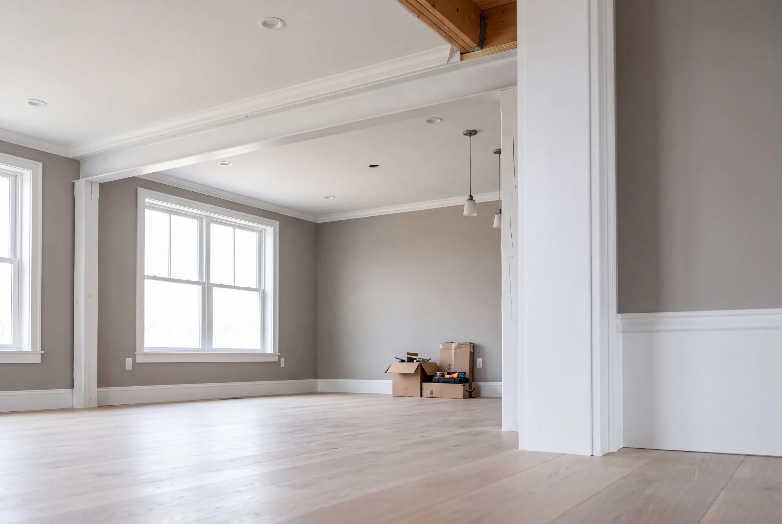 Home renovation contractor Waldoboro Maine: large empty room with gray walls, white wainscot, pendant lights and moving boxes