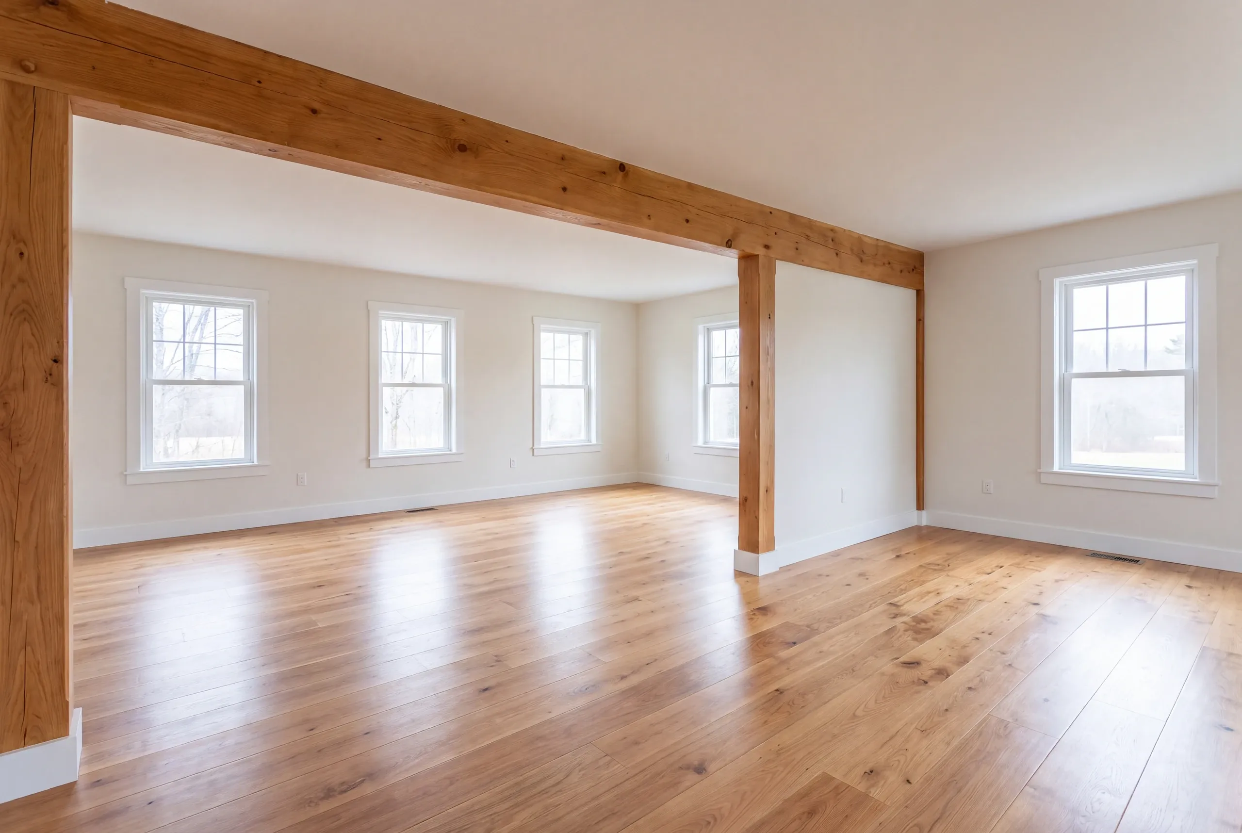 Home renovation contractor Waldoboro Maine: open room framed by exposed timber posts and beams over light oak flooring