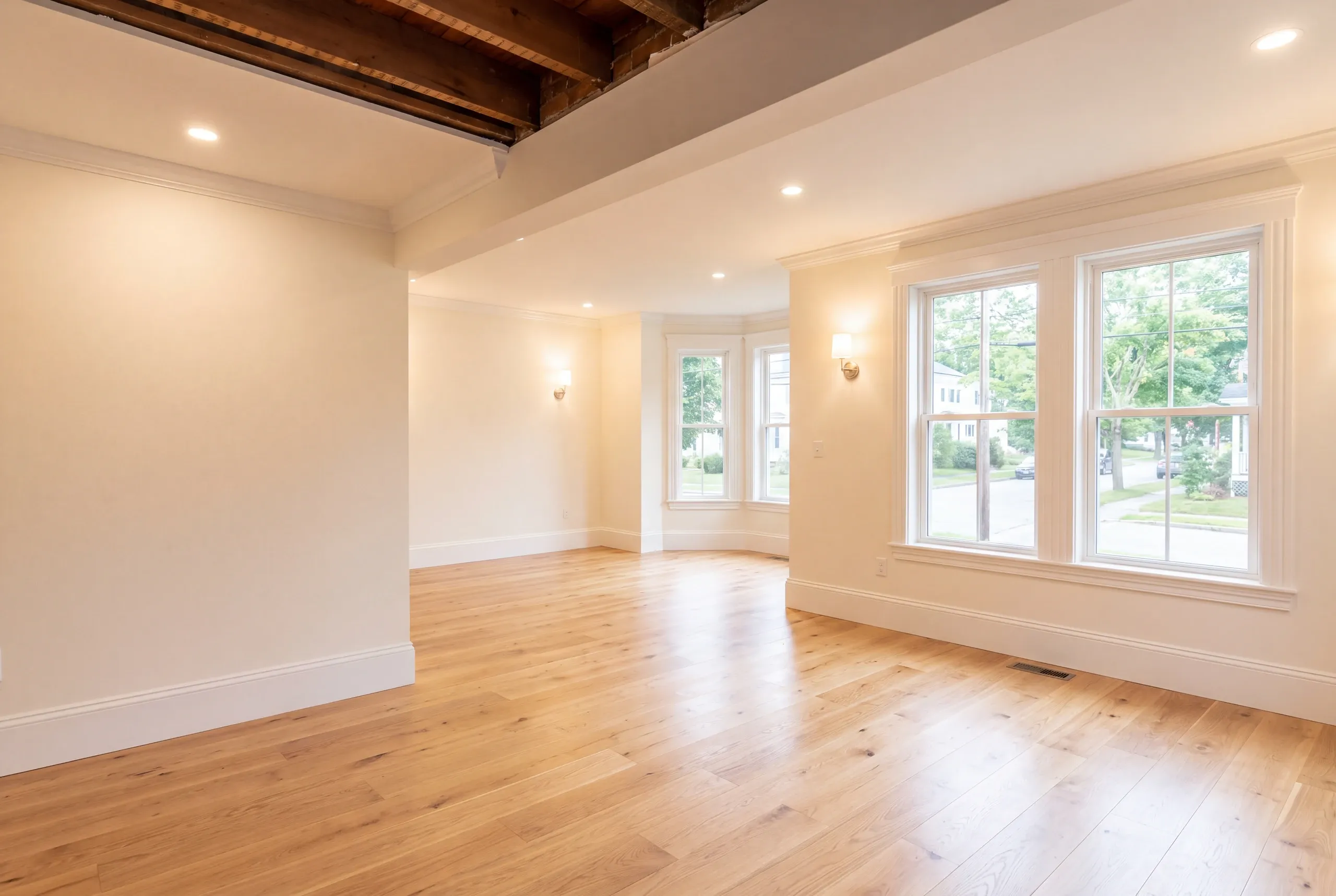 Remodeling company Waterville Maine: finished room with partly exposed dark ceiling joists, wall sconces and a bay window