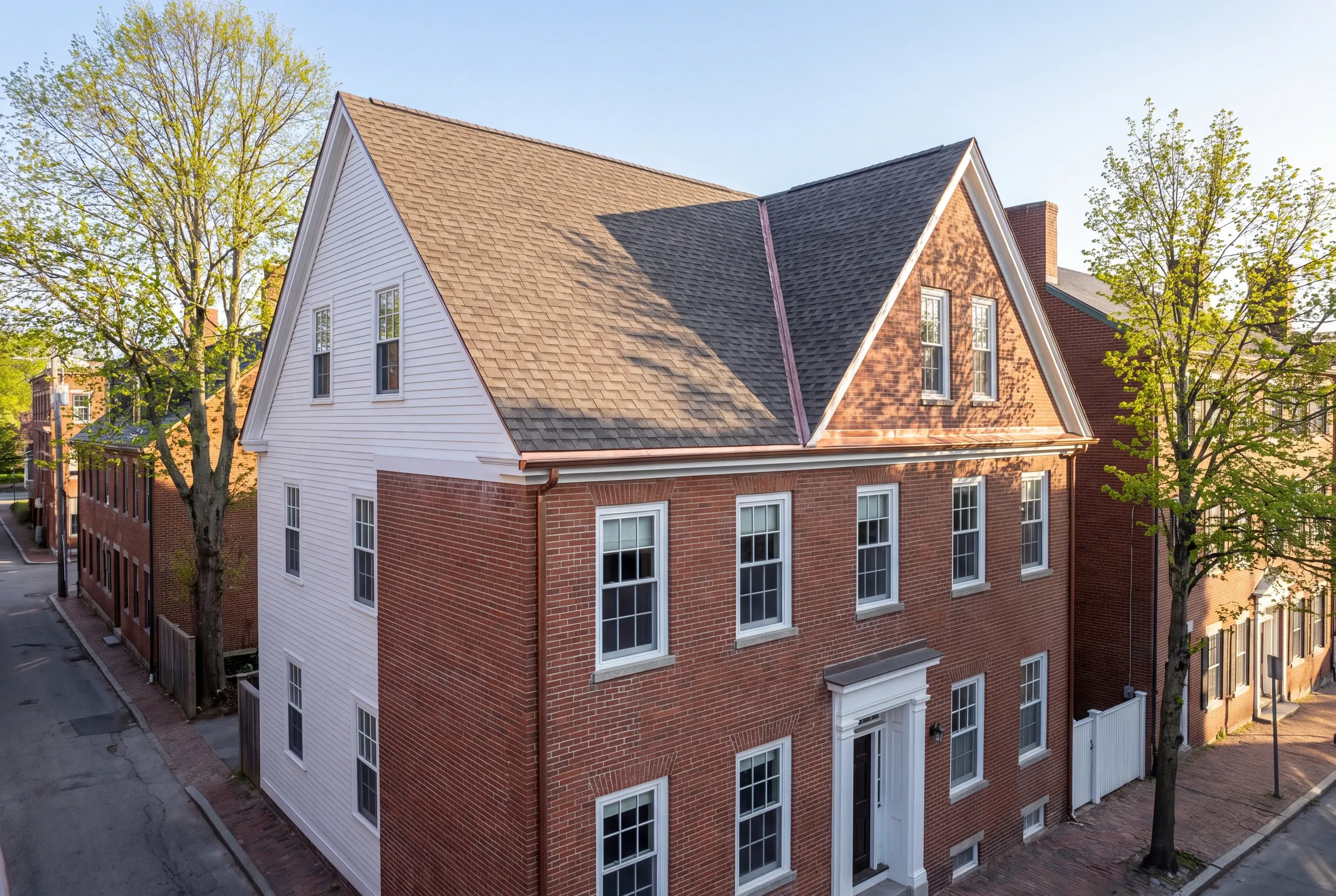 Roofing contractor in Bath, ME: brick Federal house with clapboard side and steep shingled gables meeting at a copper valley